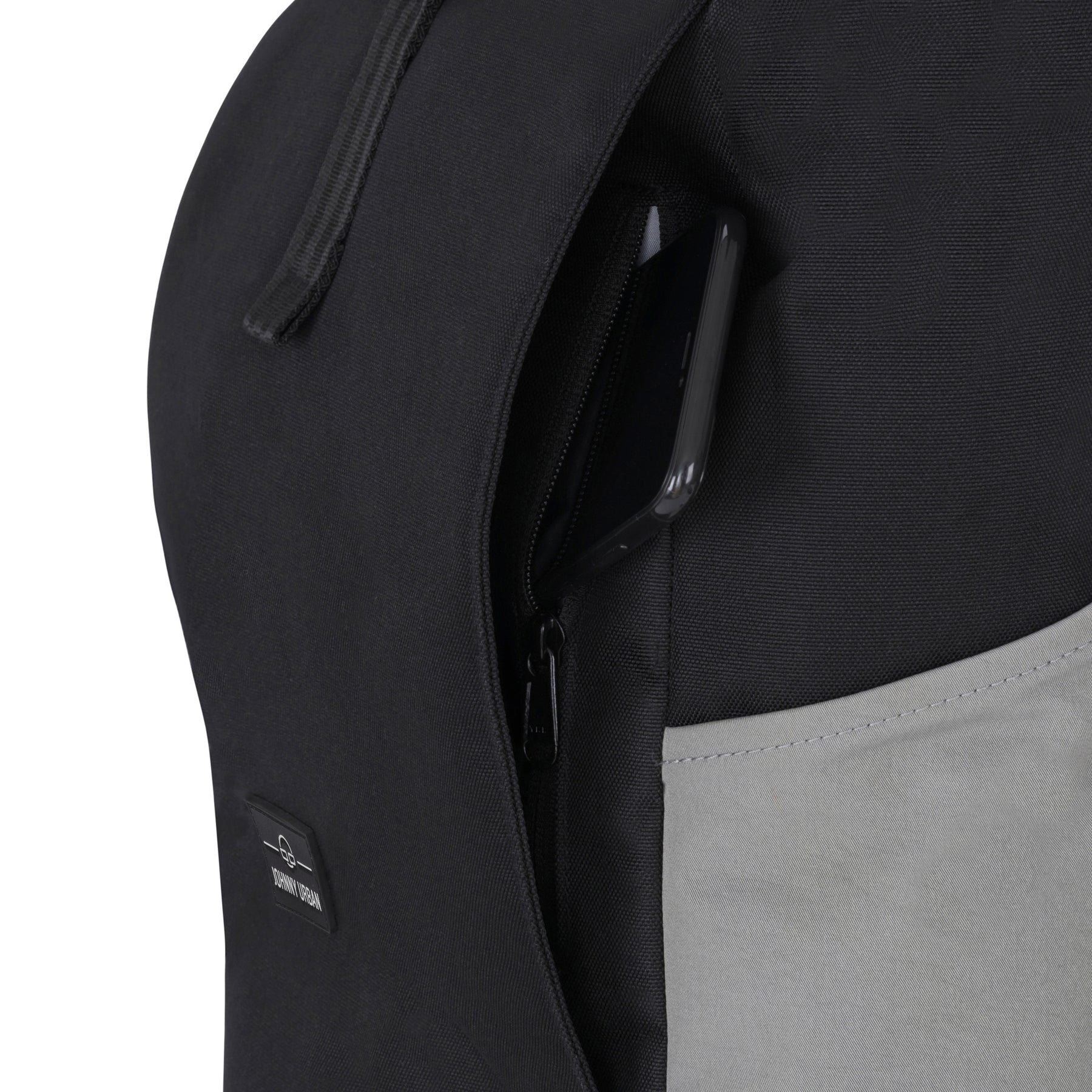 Schwarzer Rolltop Rucksack 'Allen Medium' von Johnny Urban mit seitlicher Reißverschlusstasche, in der ein Smartphone steckt