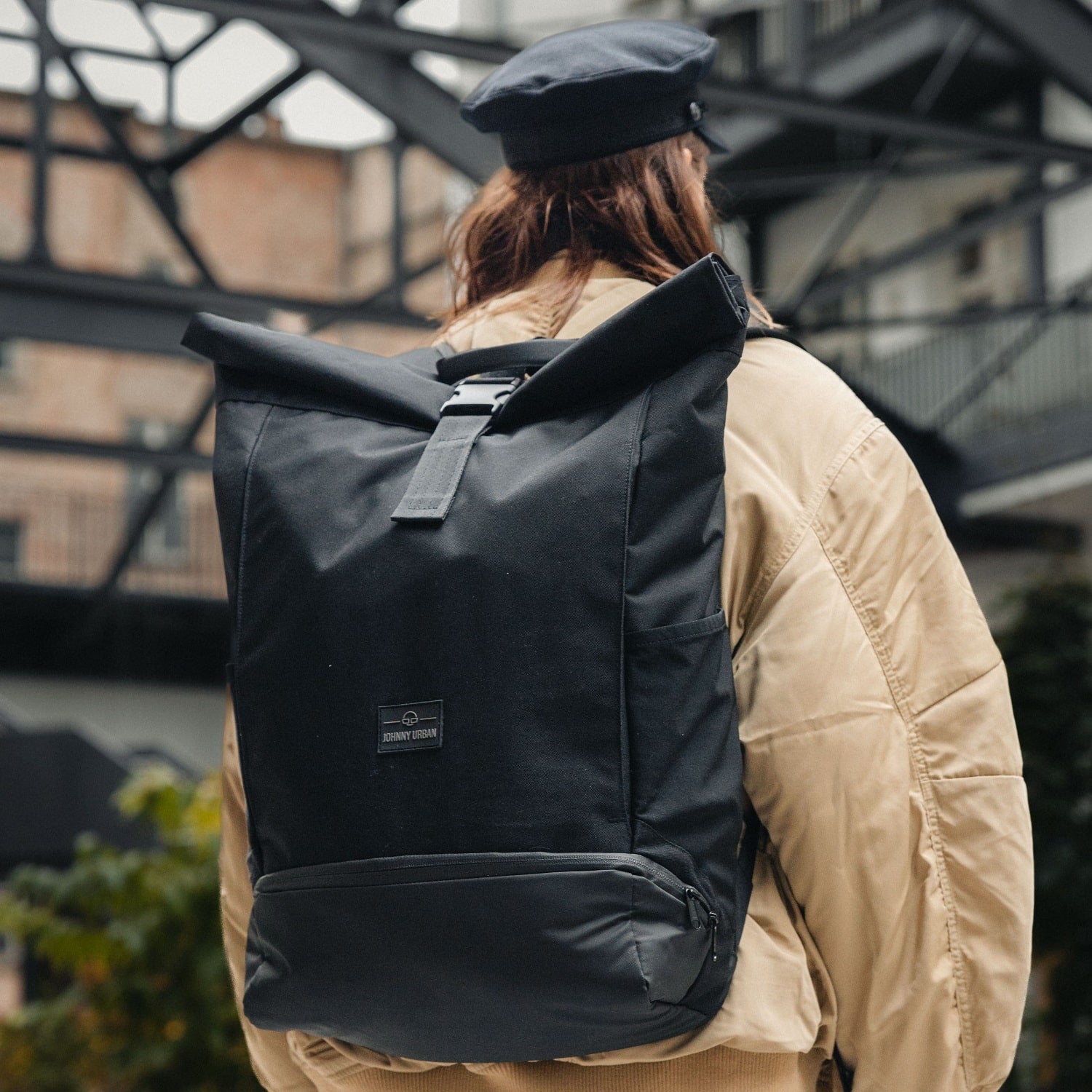 Schwarzer Rolltop Rucksack 'Allen XL' von Johnny Urban an einer Person mit hellbeiger Jacke und schwarzer Mütze