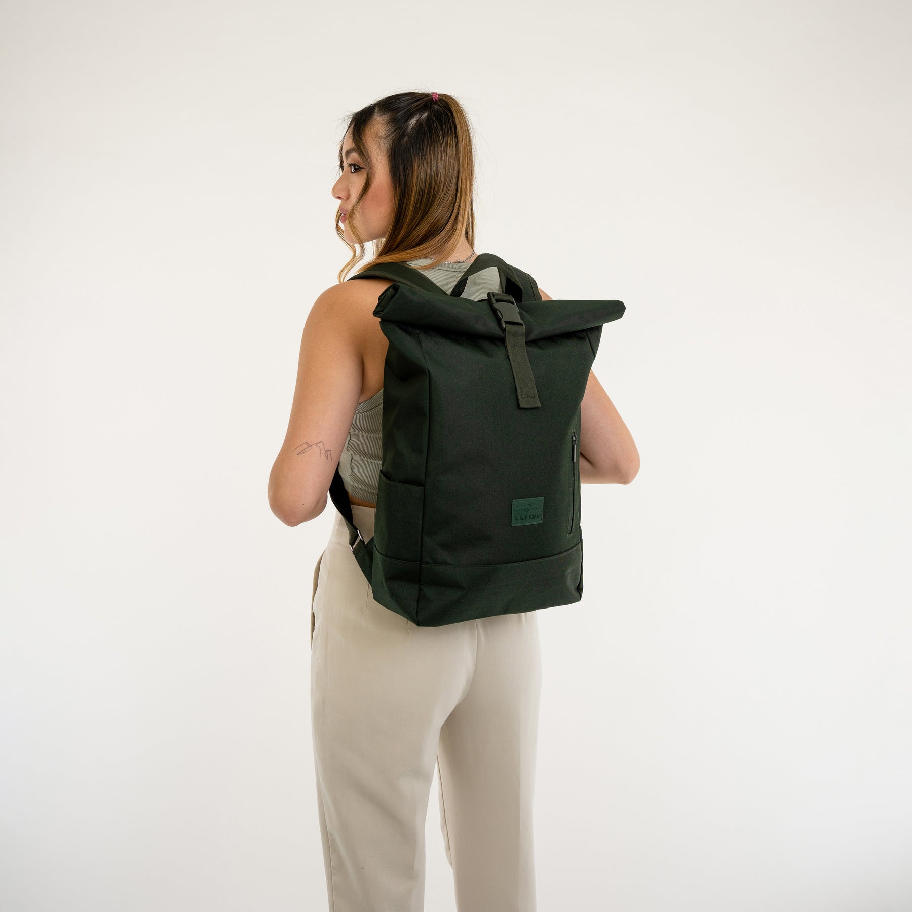 Frau von hinten mit schwarzem Rolltop Rucksack 'Robin Medium' von Johnny Urban, trägt hellbeige Hose und graues Tanktop
