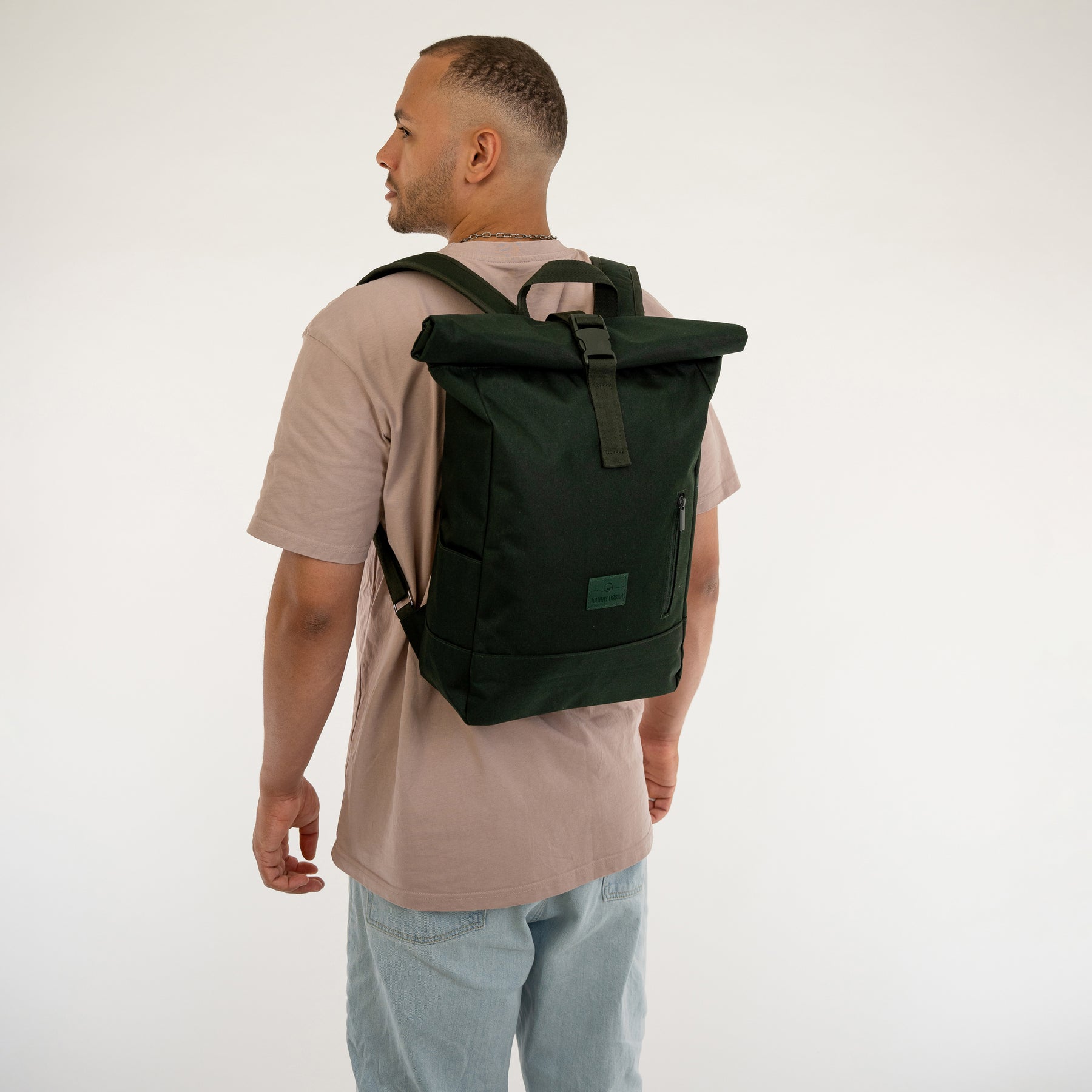 Mann von hinten mit beigem T-Shirt und blauem Jeans, trägt schwarzen Rolltop Rucksack 'Robin Medium' von Johnny Urban