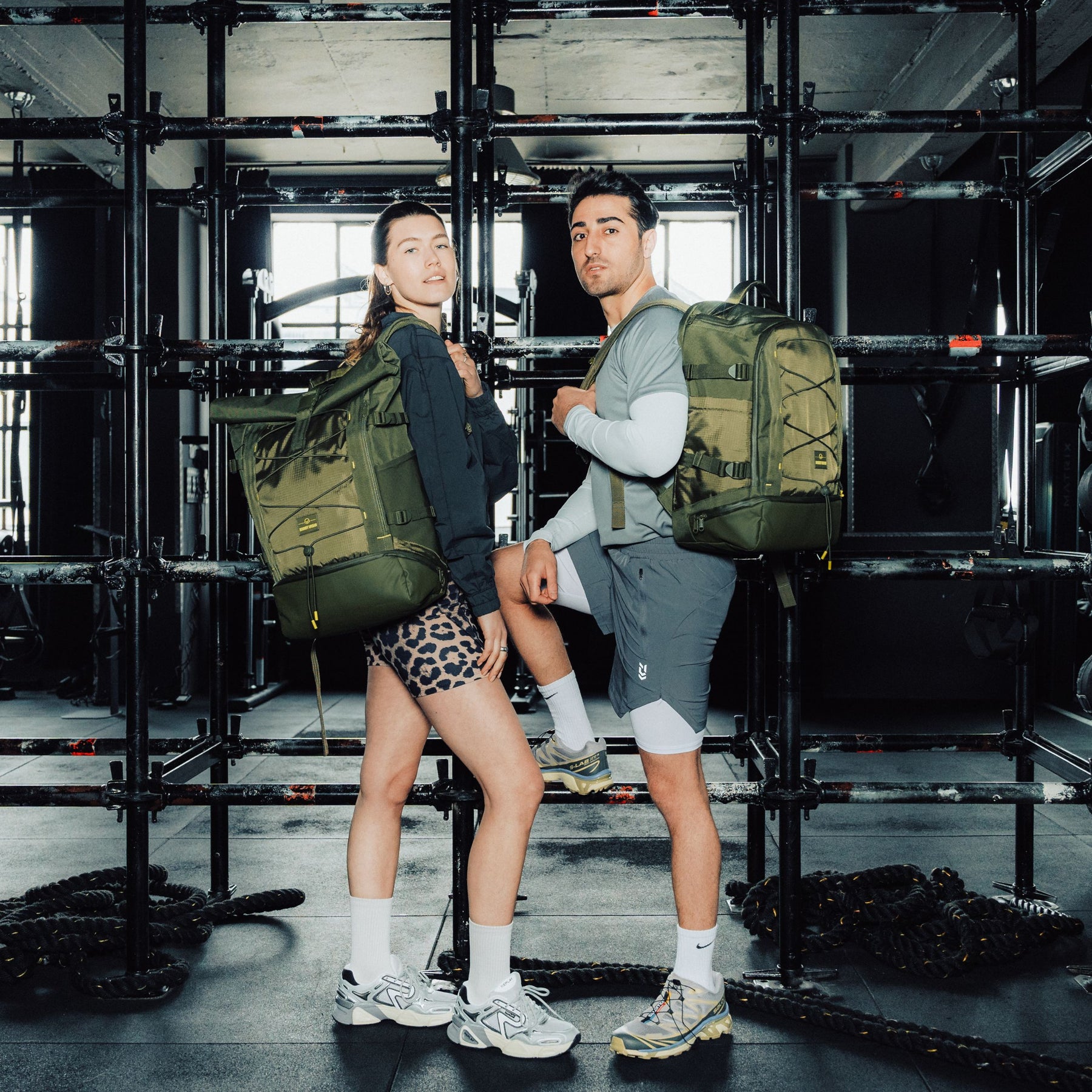 Frau und Mann in Sportkleidung mit olivgrünem Rolltop-Rucksack 'Allen Large Move' in einem Fitnessstudio