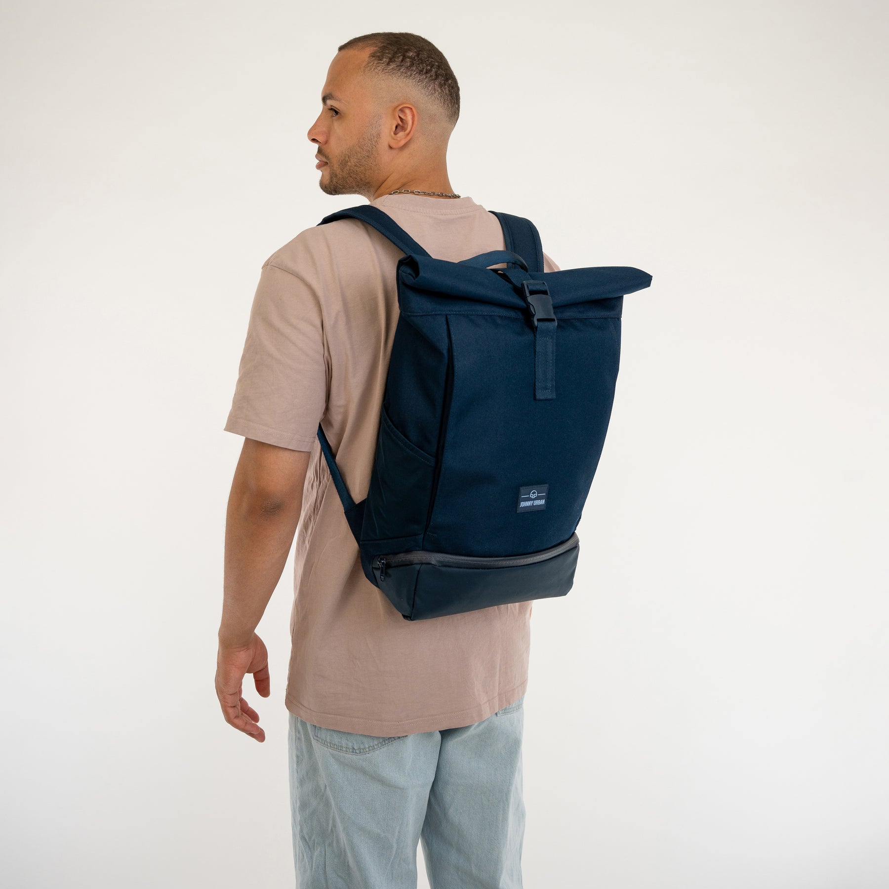 Mann von hinten mit blauem Johnny Urban Rolltop Rucksack 'Allen Medium' und beige T-Shirt