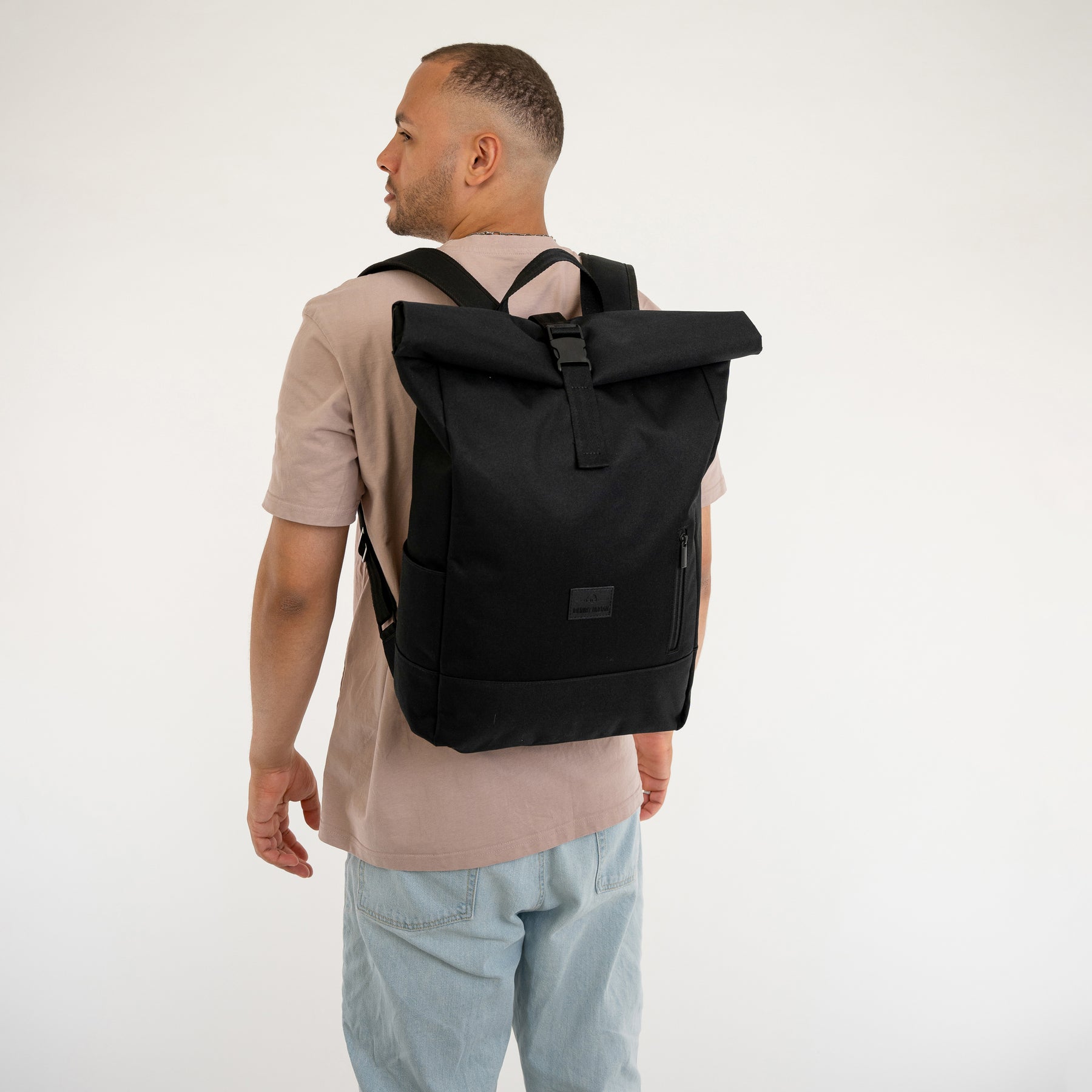 Mann von hinten mit Rolltop Rucksack 'Robin Large' in Schwarz an den Schultern