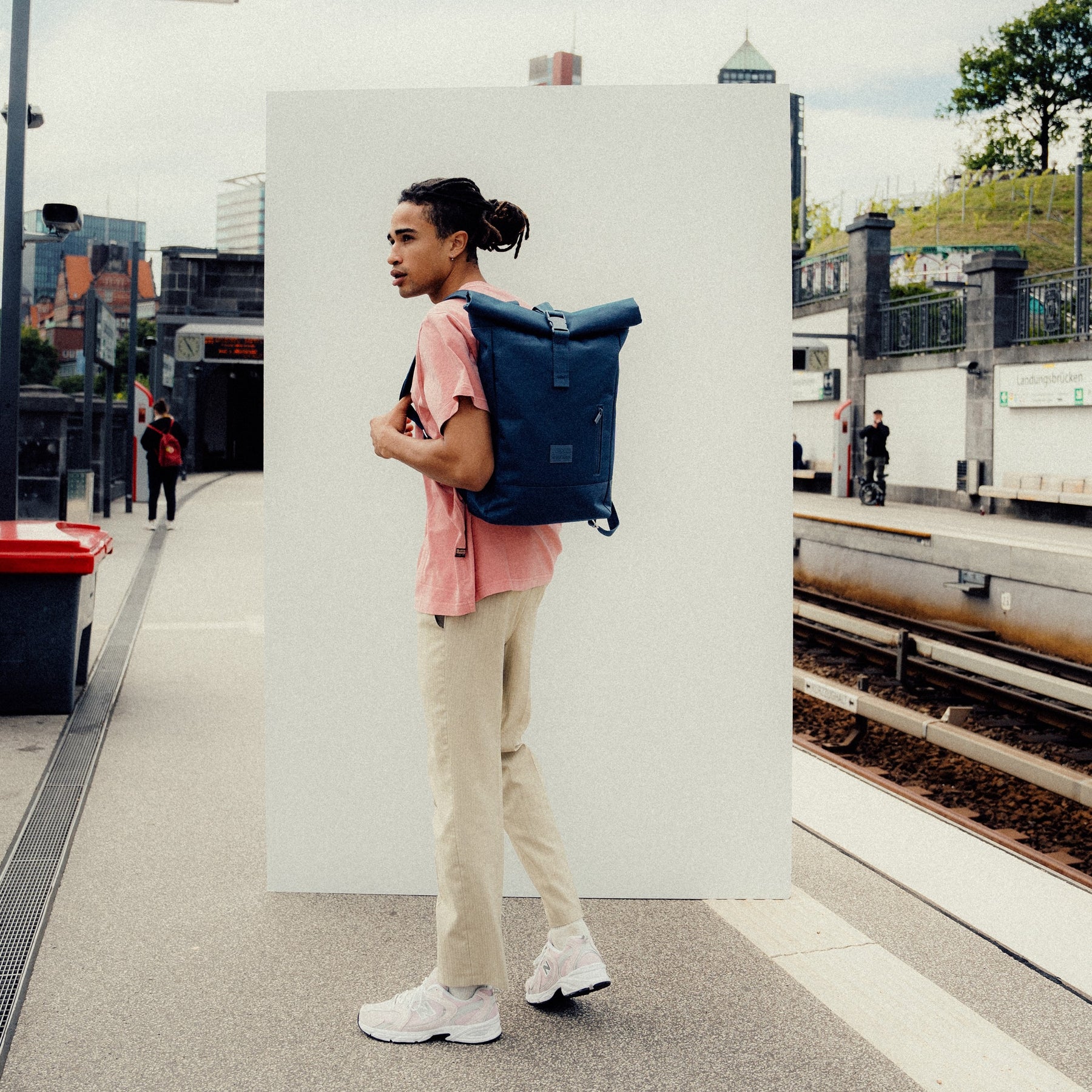 Mann mit blauem Johnny Urban Rolltop Rucksack 'Robin Medium' an einer U-Bahn-Station