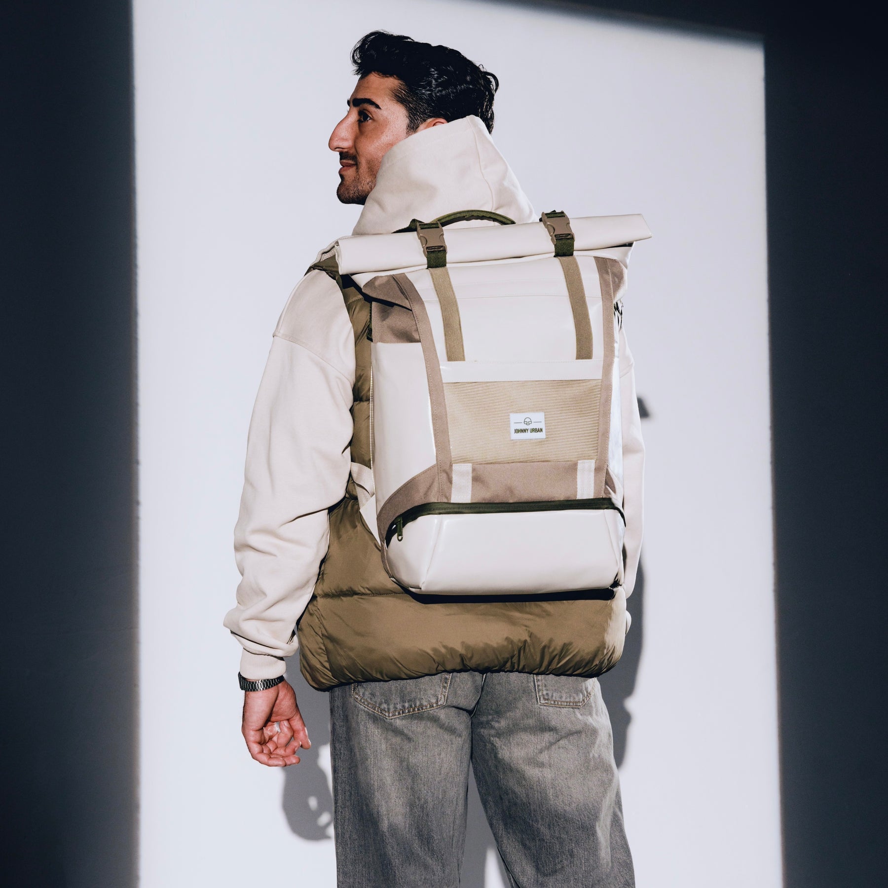 Mann trägt beigen Rolltop Rucksack 'Ashton' von Johnny Urban, dazu beige Jacke und graue Jeans
