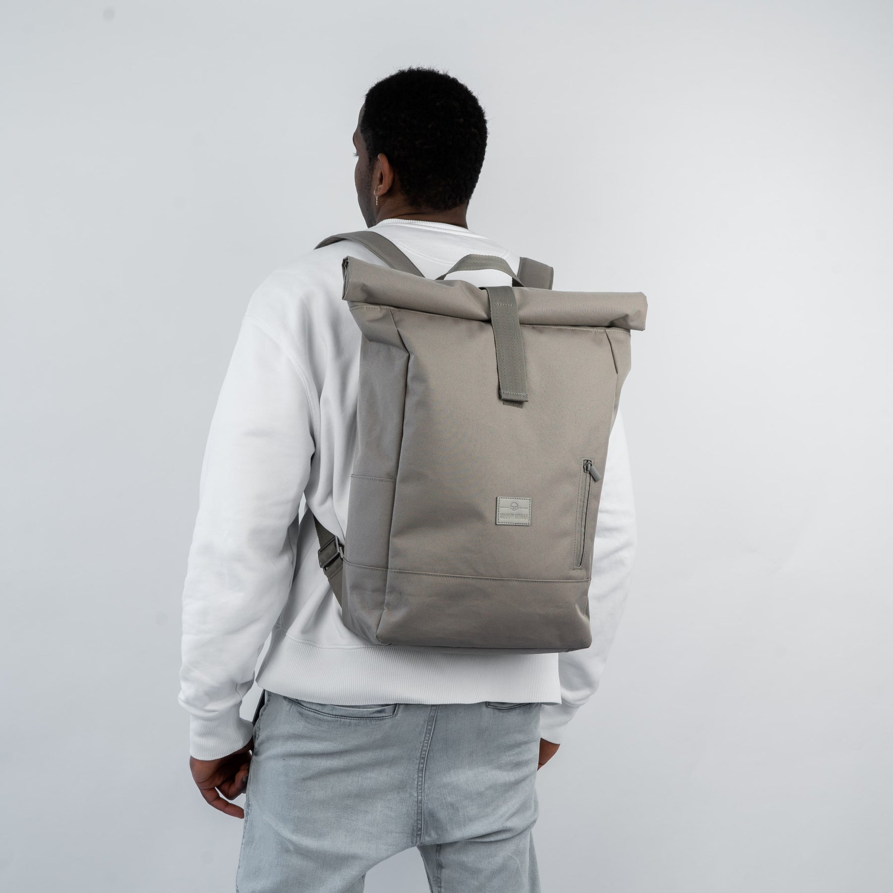 Mann trägt beigen Rolltop Rucksack 'Robin Large' von Johnny Urban mit Fronttasche und gepolsterten Schultergurten