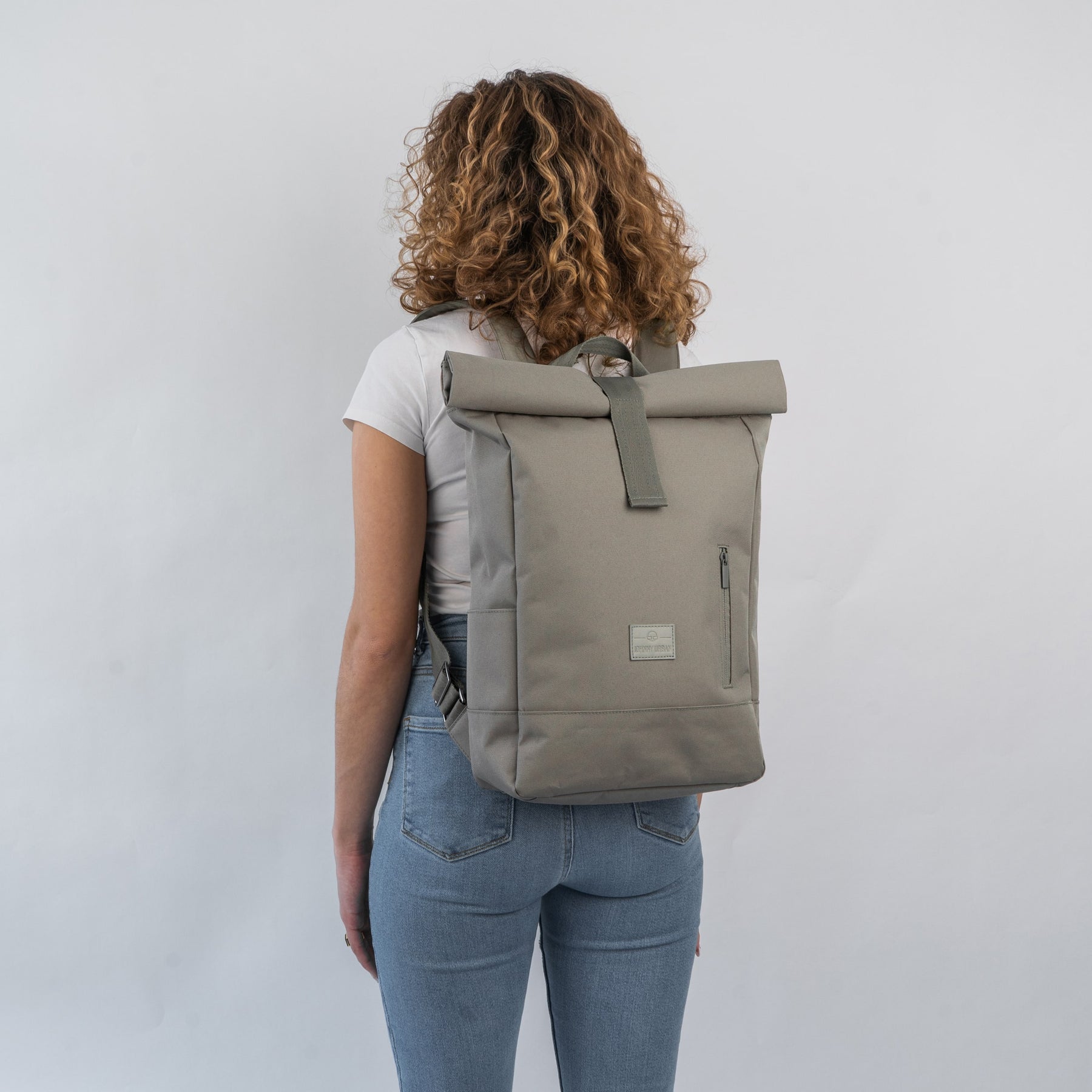 Frau mit lockigem Haar trägt den Johnny Urban Rolltop Rucksack 'Robin Medium' in desert-grey, Rückenansicht