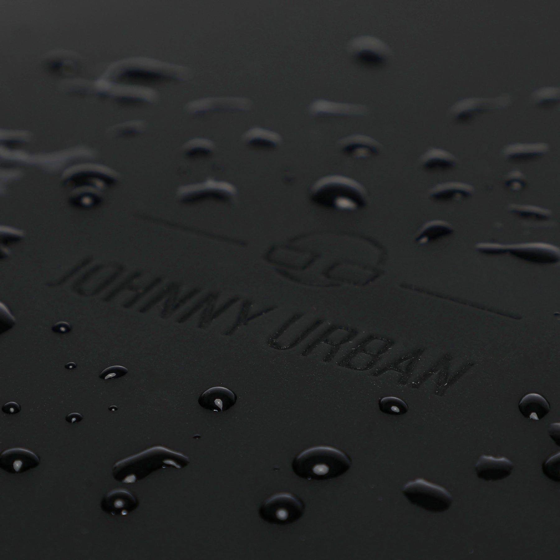 Wasserabweisende Oberfläche mit geprägtem Johnny Urban Logo auf schwarzem Material des Rolltop Rucksacks Harvey Large