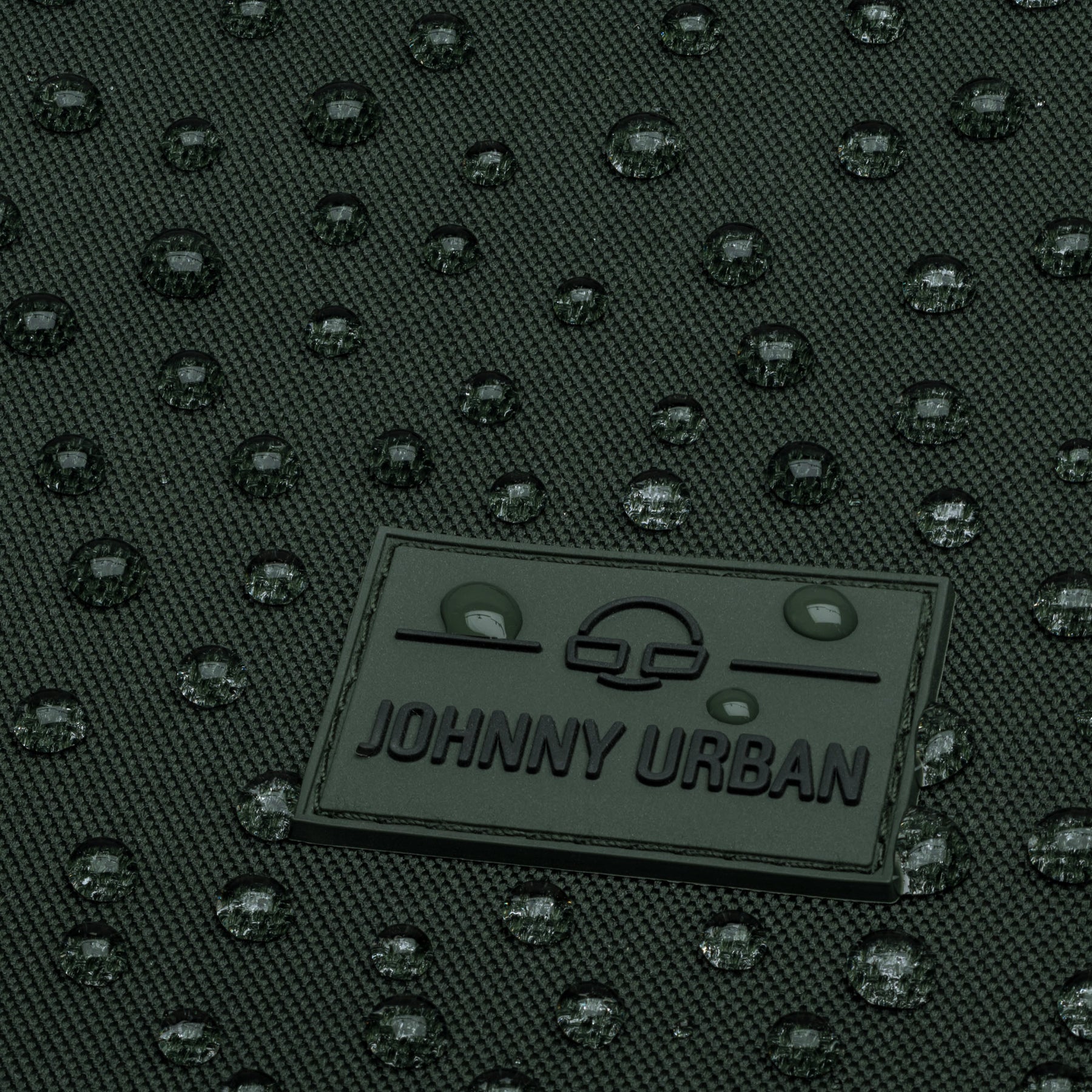 Wasserabweisendes, grünes Material mit Johnny Urban Logo und Wasserperlen