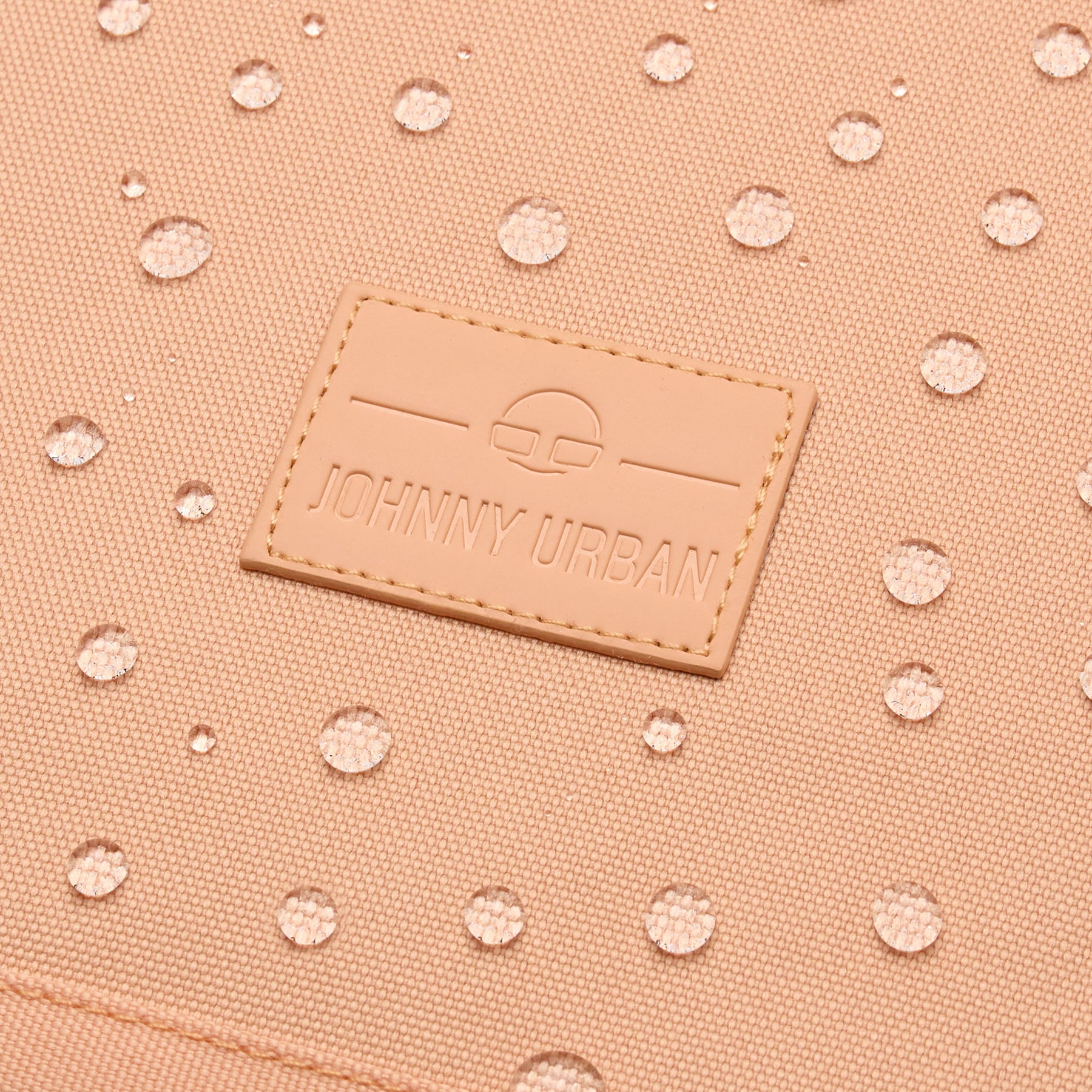 Nahe Aufnahme eines wasserabweisenden, pfirsichfarbenen Johnny Urban Rolltop Rucksacks mit sichtbarem Logo