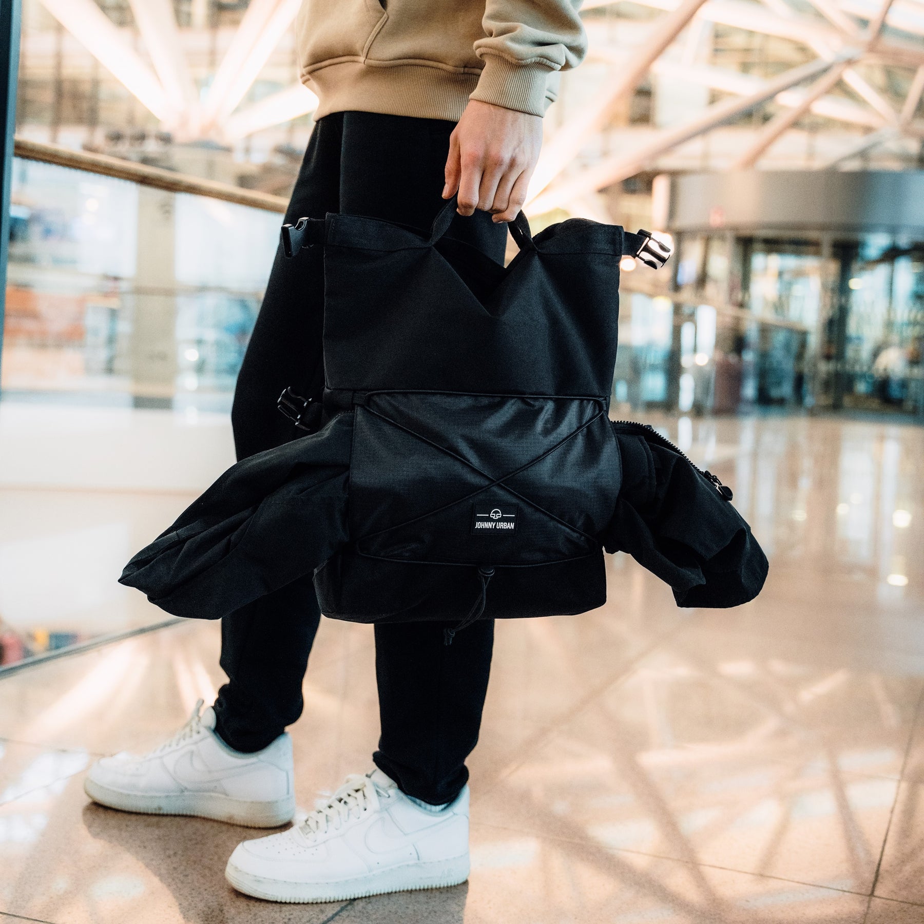 Person hält schwarze Johnny Urban Umhängetasche 'Dylan' mit Rolltop und zusätzlichem Stauraum