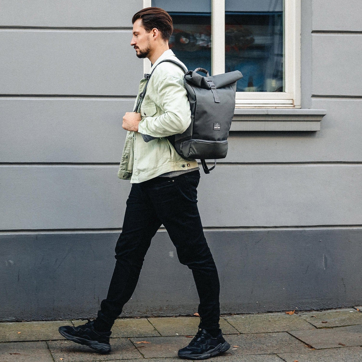 Mann trägt dunkelgrauen Rolltop Rucksack 'Allen Medium' von Johnny Urban, urbaner Hintergrund