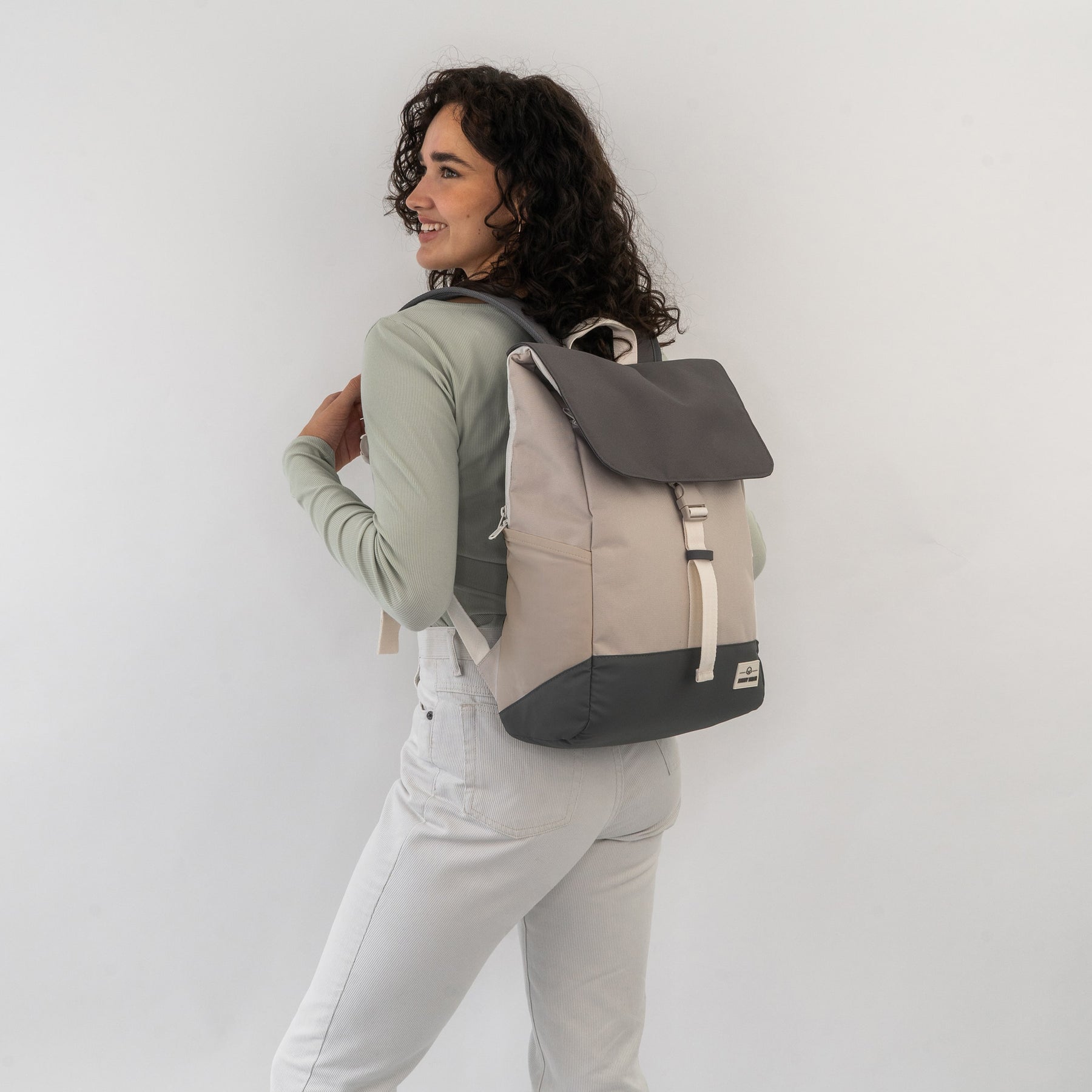 Frau trägt den beige-sandfarbigen Rucksack 'Mika' mit dunklem Deckel und Boden