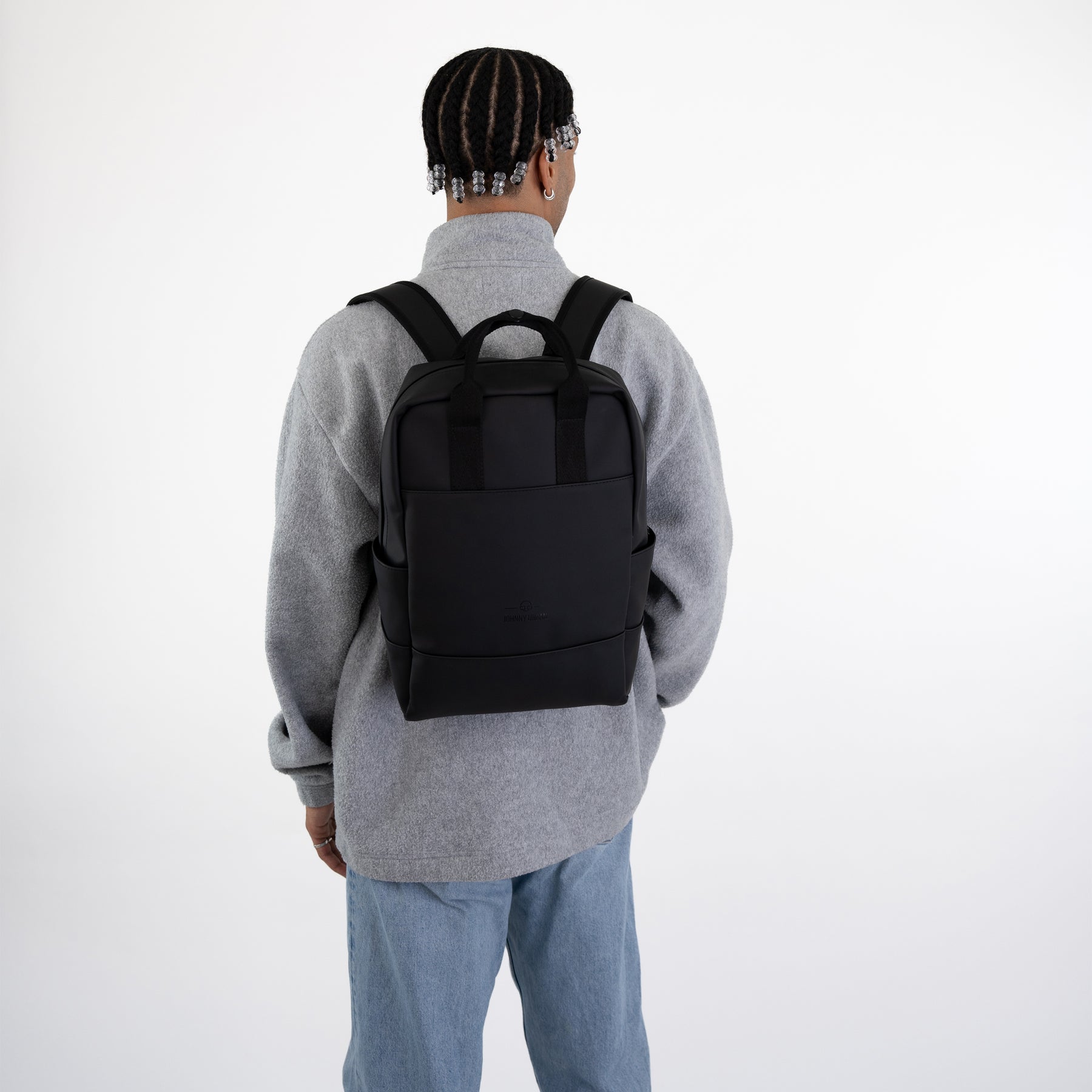 Schwarzer Rucksack 'Hailey' von Johnny Urban auf Rücken einer Person mit grauem Pullover und blauer Jeans