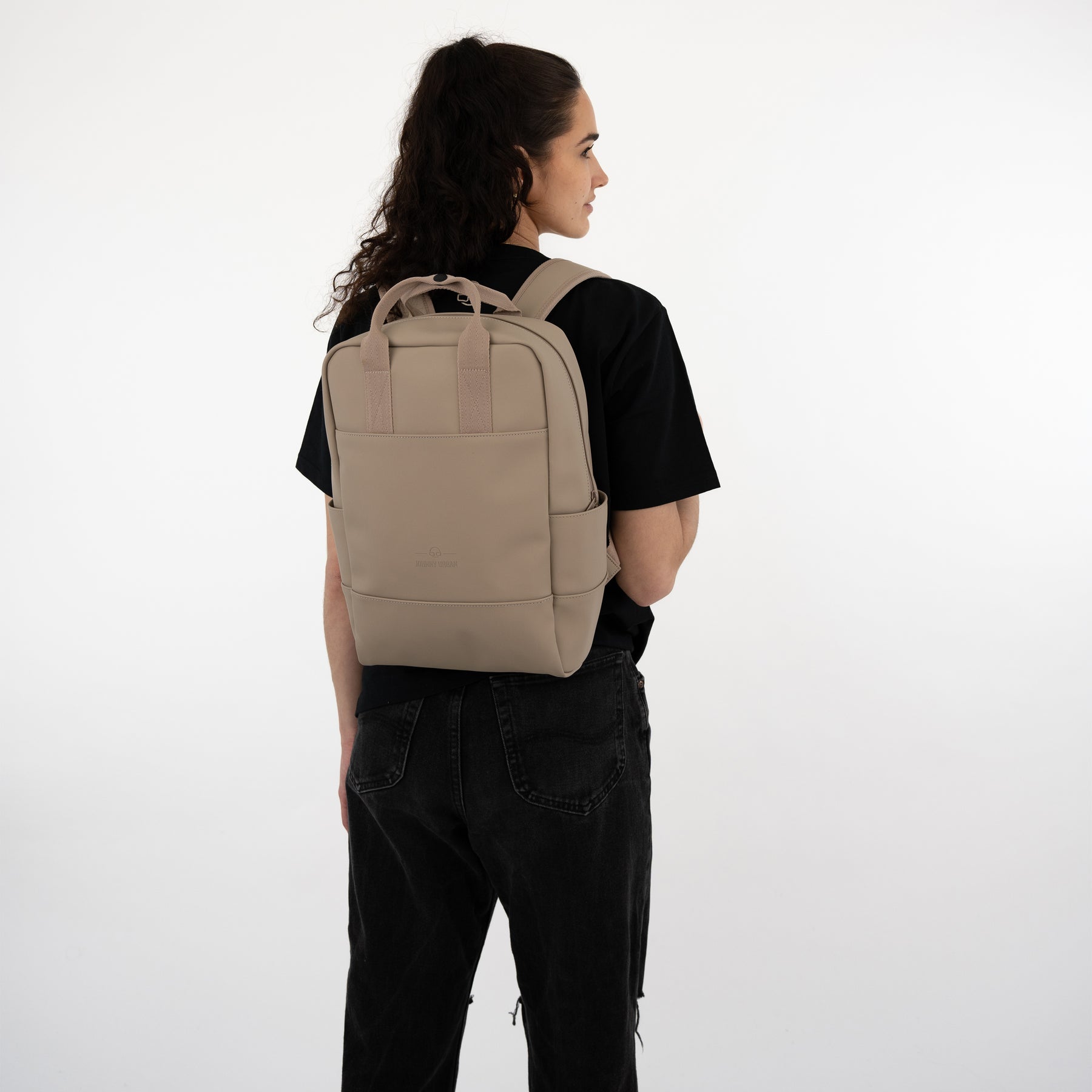 Beige Rucksack 'Hailey' von Johnny Urban getragen von Frau in schwarzem T-Shirt und schwarzen Jeans