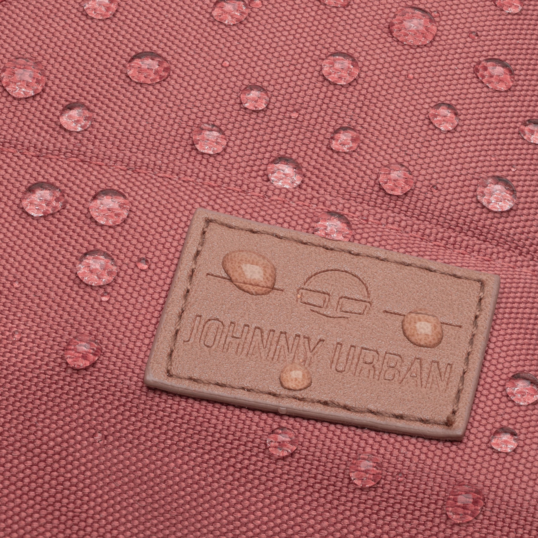 Nahaufnahme des roten wasserfesten Damenrucksacks ‚Mia‘ mit Johnny Urban Lederetikett und Wassertröpfchen