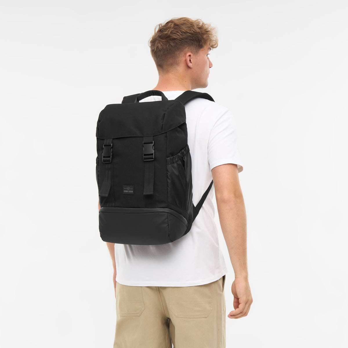 Mann trägt schwarzen Rucksack 'Nico' von Johnny Urban, weiße T-Shirt, beige Hose