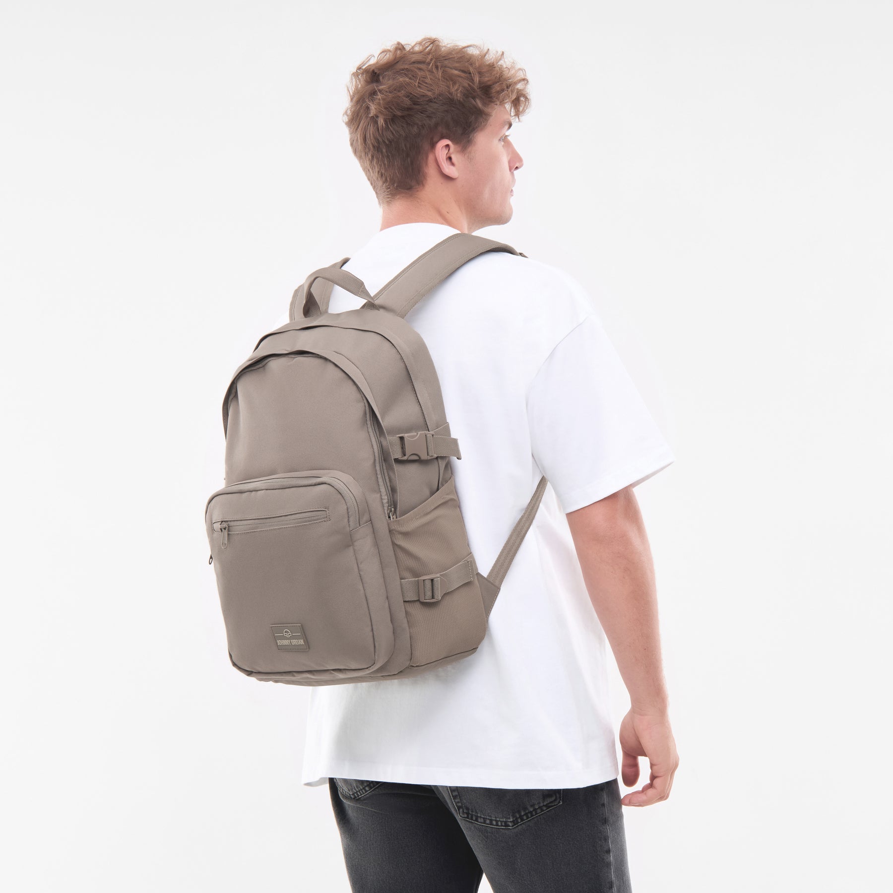Herren trägt Rucksack 'Lian' in desert-grau auf weißem T-Shirt und schwarzen Jeans