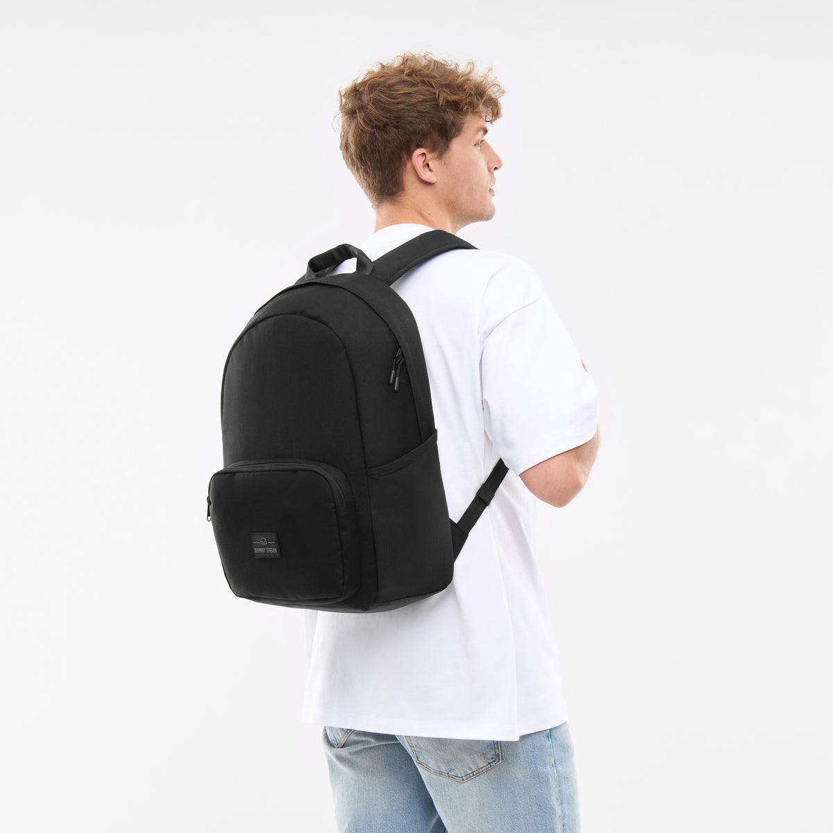 Mann trägt schwarzen Rucksack 'Mo' von Johnny Urban, weißes T-Shirt, Jeans