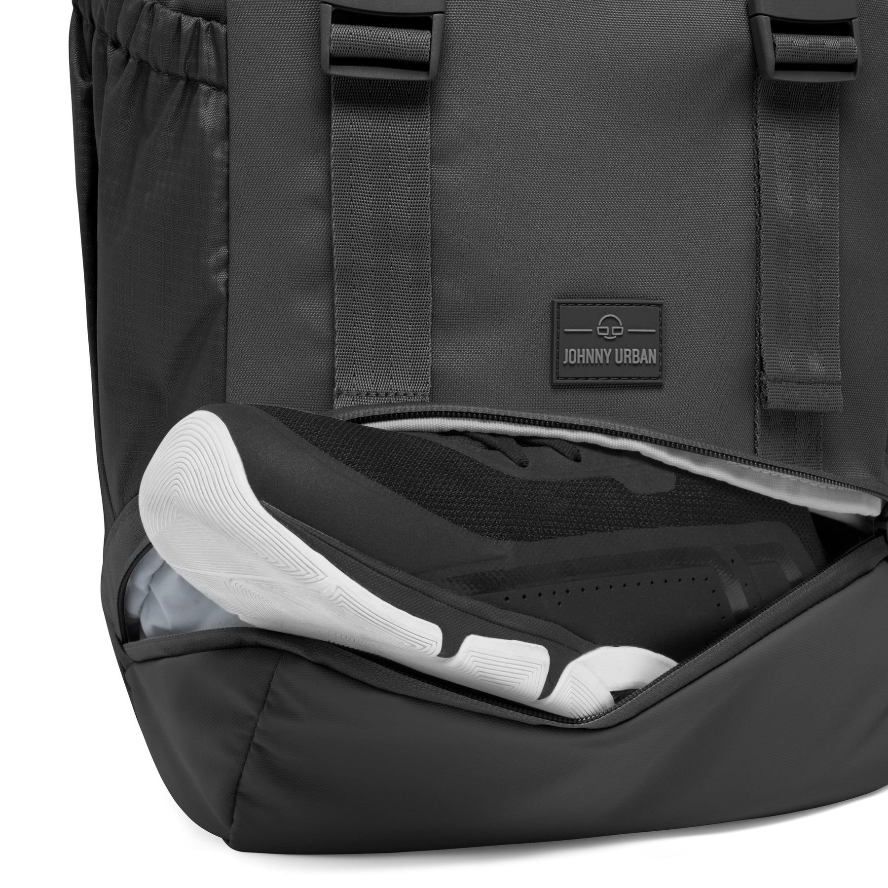 Schwarzer Johnny Urban Rucksack 'Nico' mit offenem Schuhfach, das einen schwarzen Sportschuh mit weißer Sohle enthält