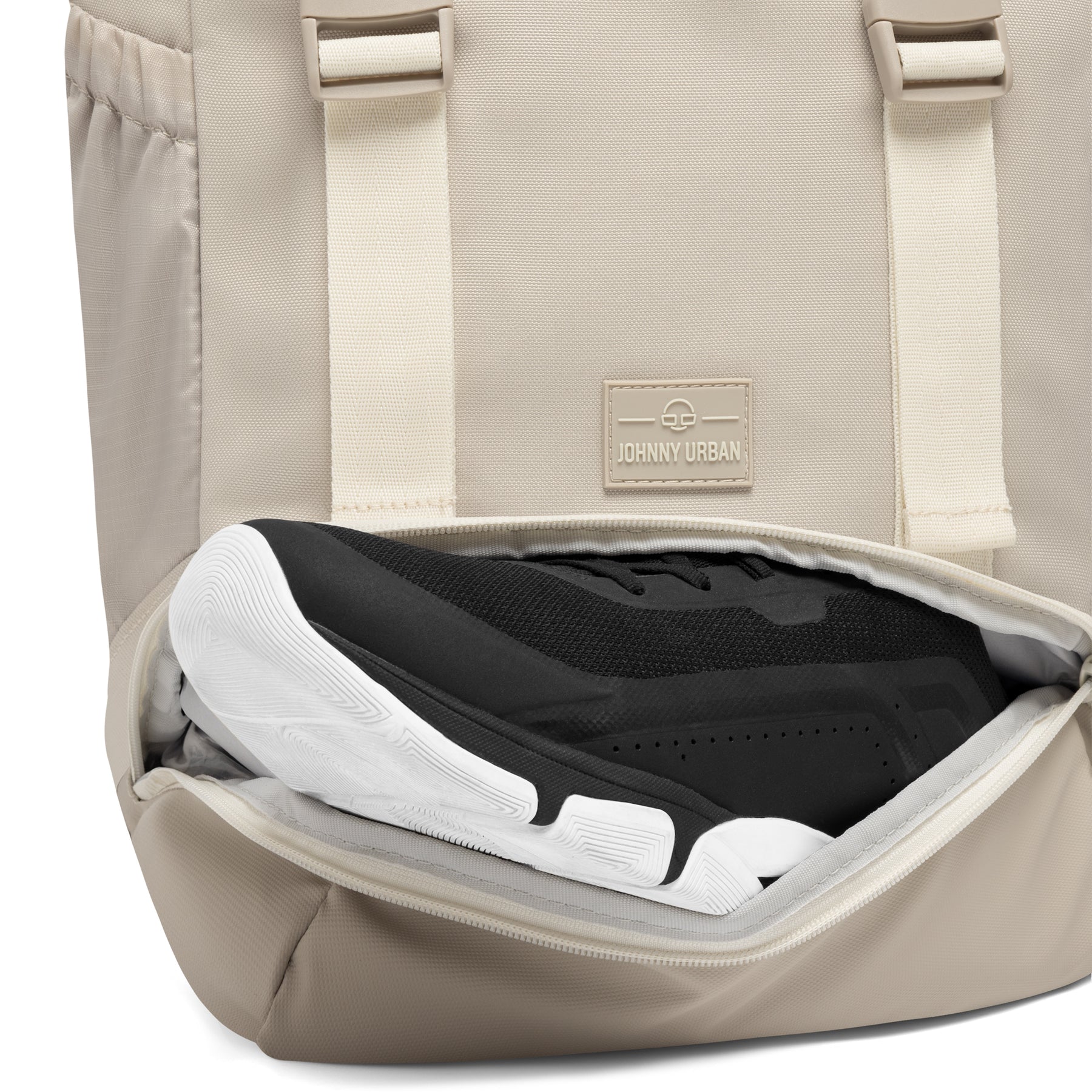 Beiger Johnny Urban Rucksack 'Nico' mit unterem Reißverschlussfach, das einen schwarzen Sportschuh zeigt
