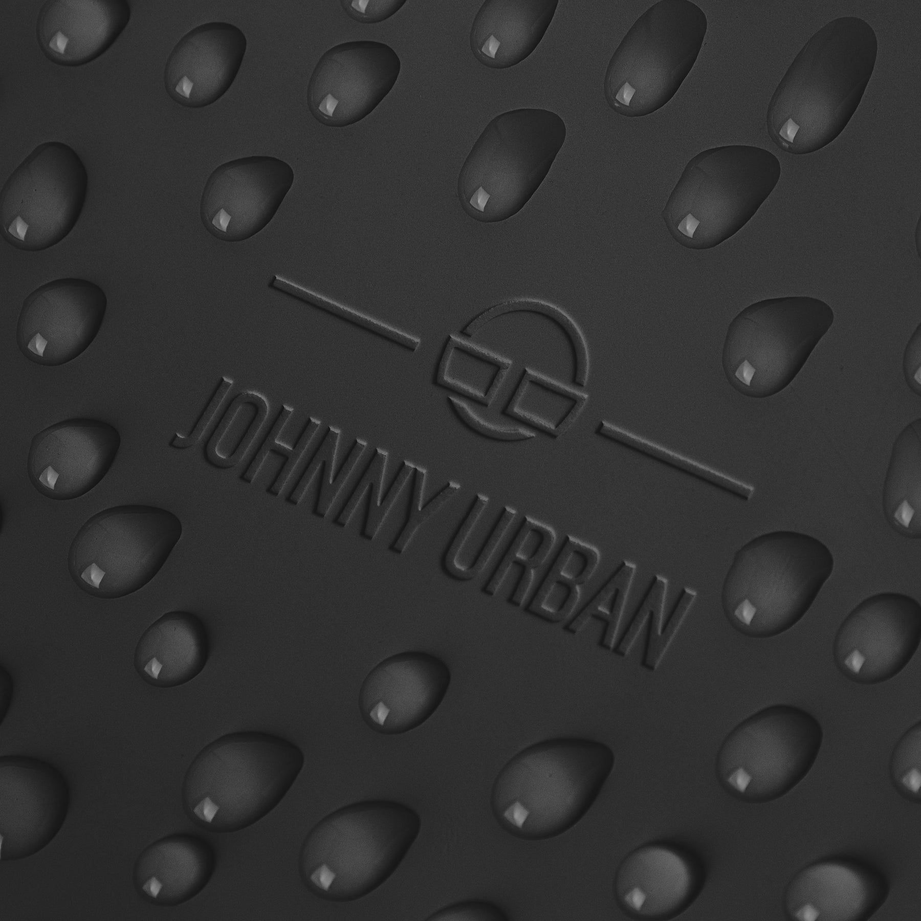 Nahaufnahme des Johnny Urban Logos auf dem wasserabweisenden schwarzen Rucksack Finley mit Wasserperlen