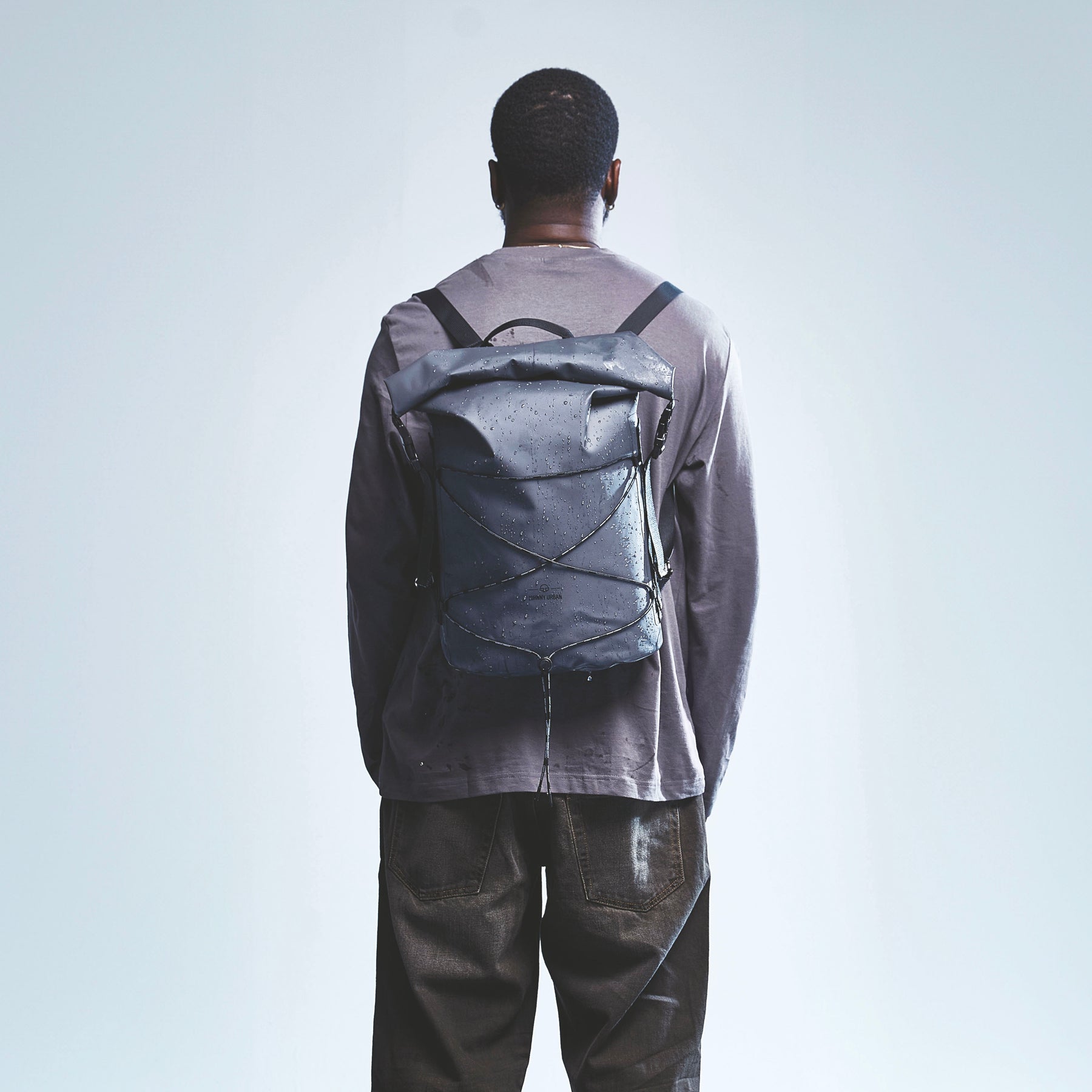 Mann mit wasserabweisendem schwarzen Rolltop Rucksack 'Myles' von Johnny Urban von hinten