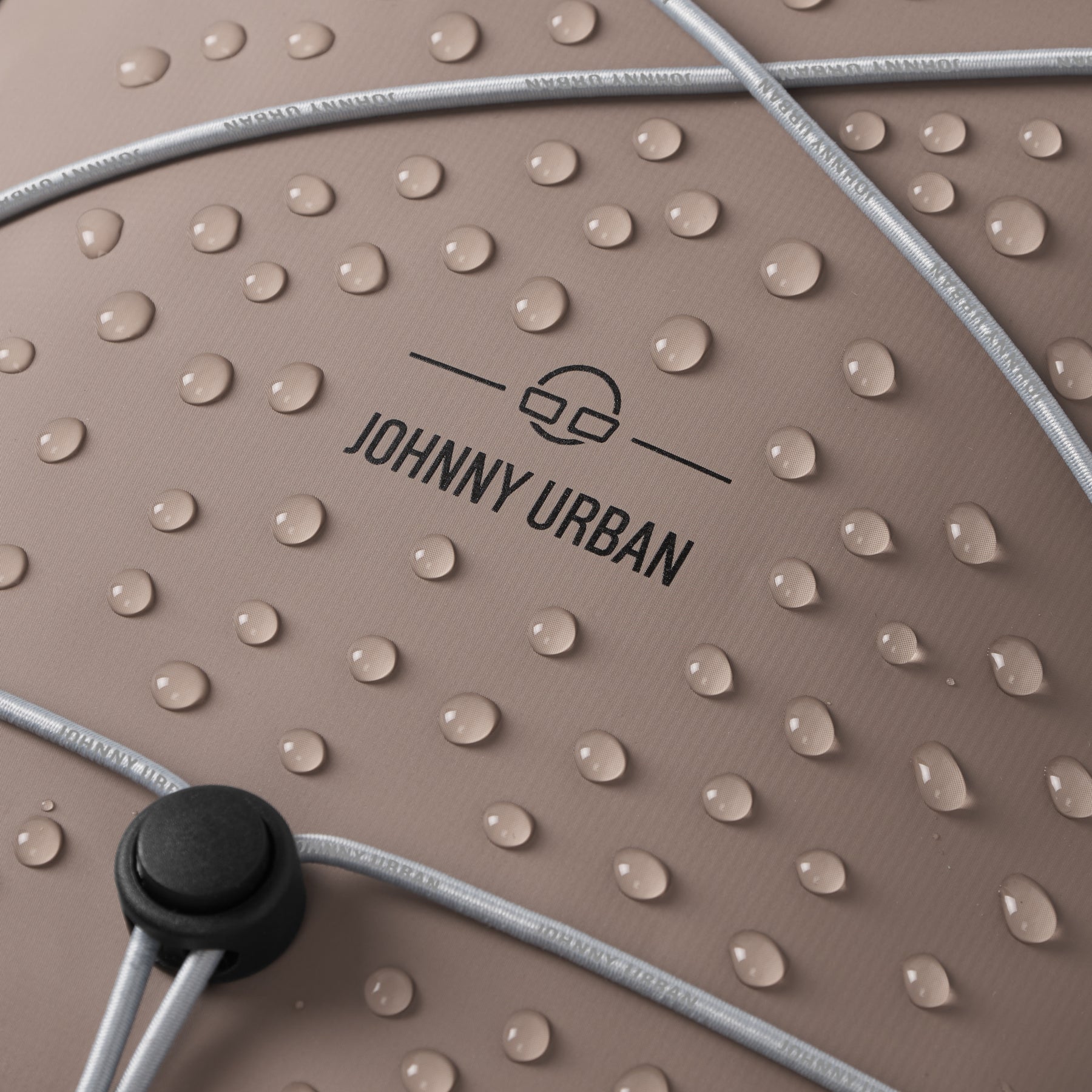 Nahaufnahme des wasserdichten Johnny Urban Rolltop Rucksacks 'Myles' mit Wassertropfen auf der Oberfläche und Gummizug