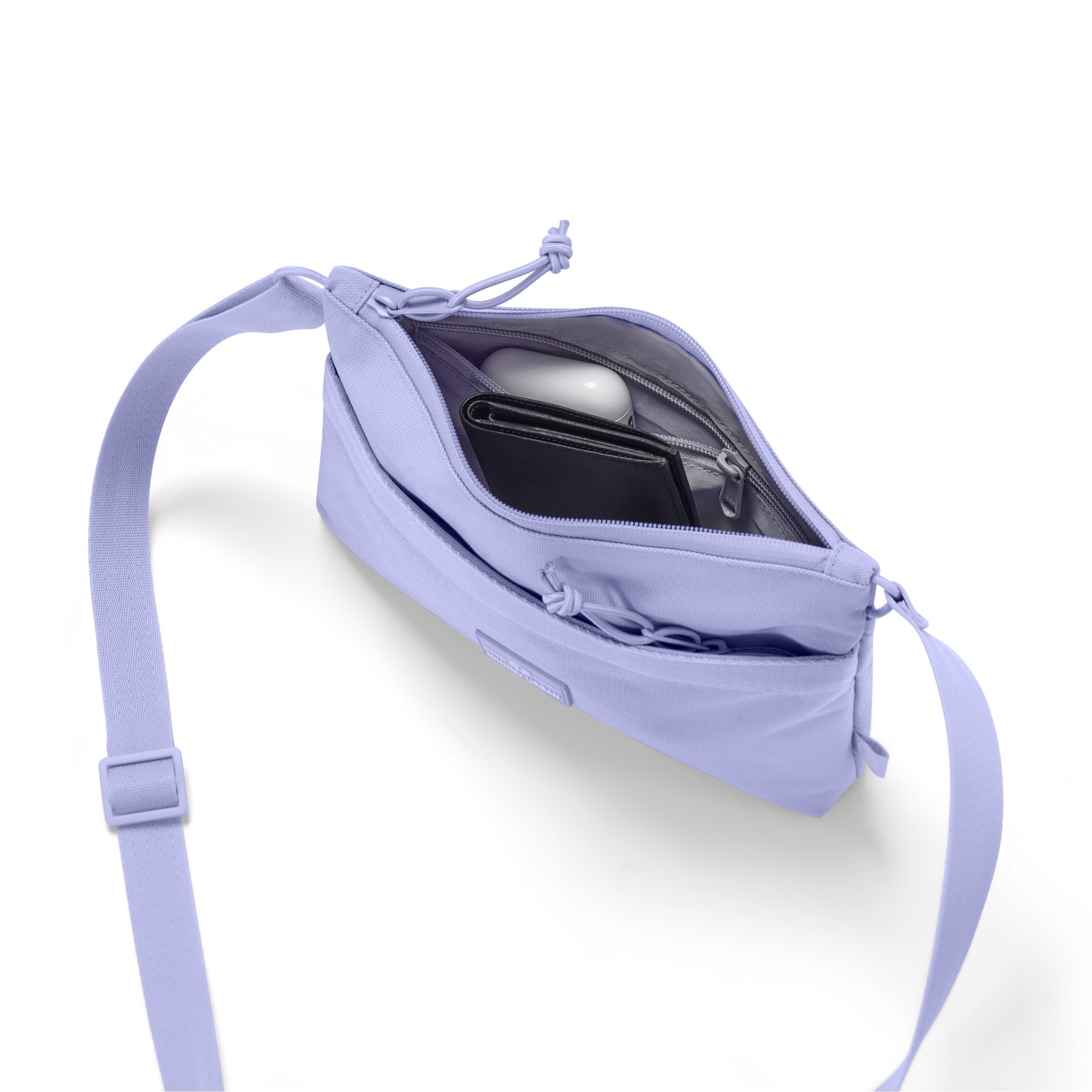 Fliederfarbene Umhängetasche 'Drew' mit geöffnetem Hauptfach, darin schwarze Geldbörse und weiße kabellose Kopfhörer