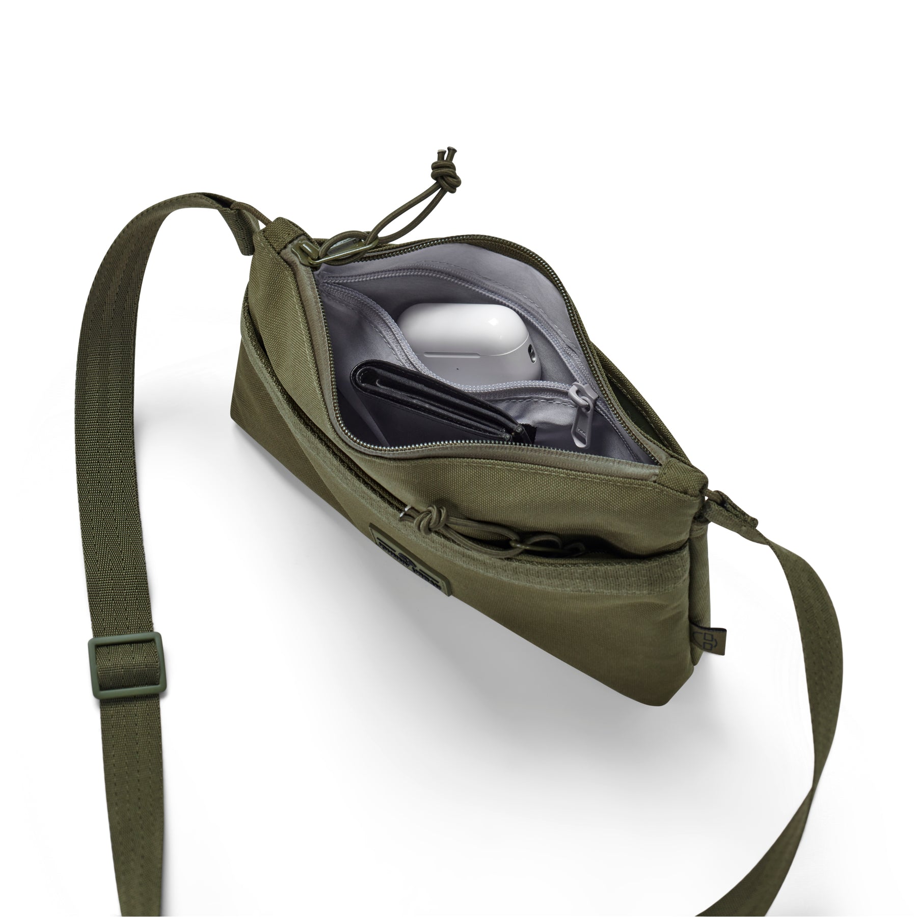 Umhängetasche "Drew" in Olivgrün mit Reißverschluss offen, zeigt Innenfach mit AirPods und Geldbörse