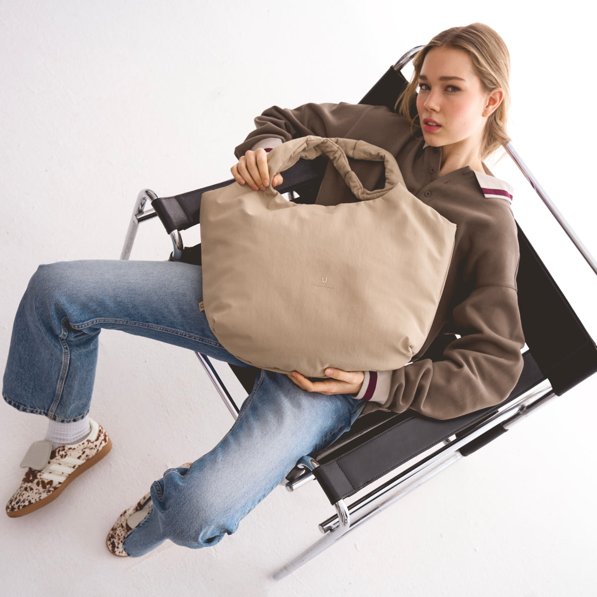 Unser weibliches Model präsentiert hier die Shopper-Tote-Bag "Cleo" in beige.