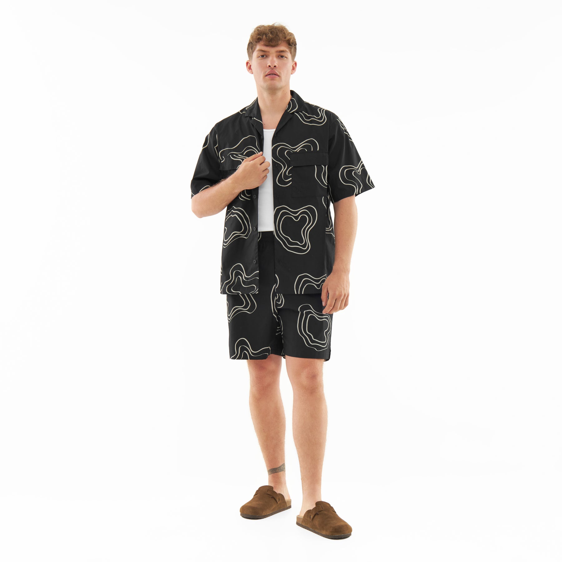 Mann trägt schwarze Shorts 'Spencer' mit weißem abstraktem Muster und passendes Hemd