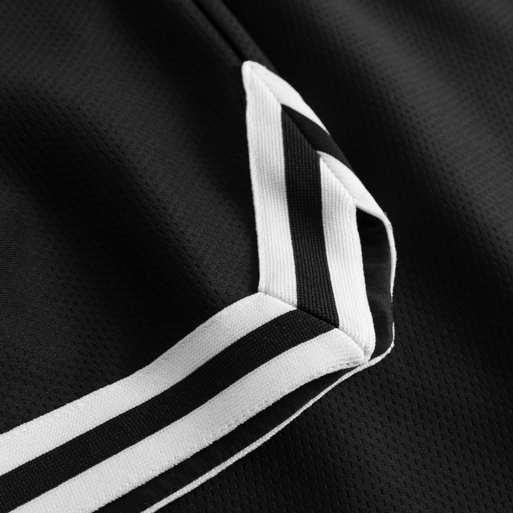 Schwarzer Stoff mit weiß-schwarzem Streifenmuster an der Kante eines Kleidungsstücks aus dem Set 'Parker'