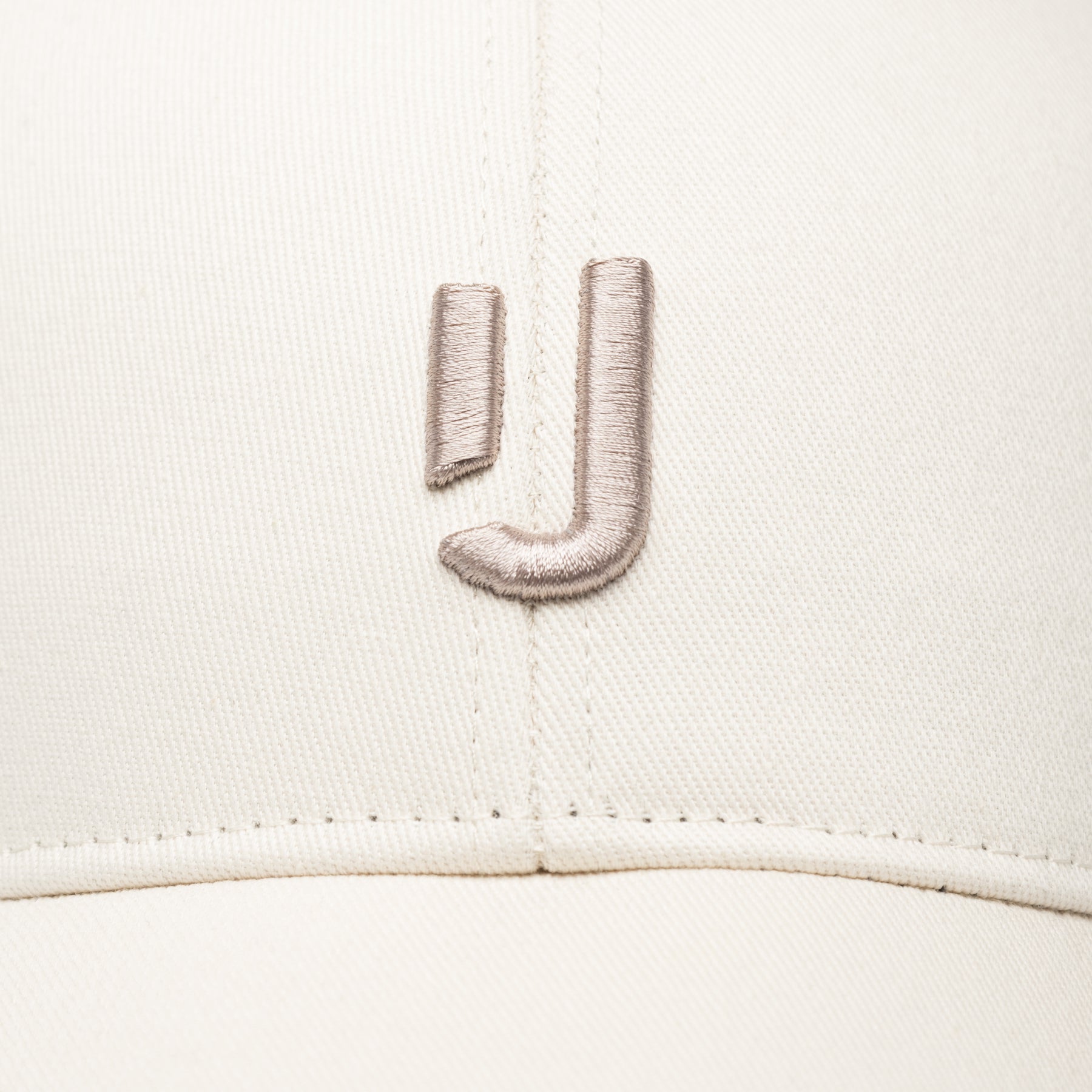 Cremefarbene Baumwollcap 'Jason' mit beigem aufgesticktem Logo aus zwei Strichen auf der Vorderseite