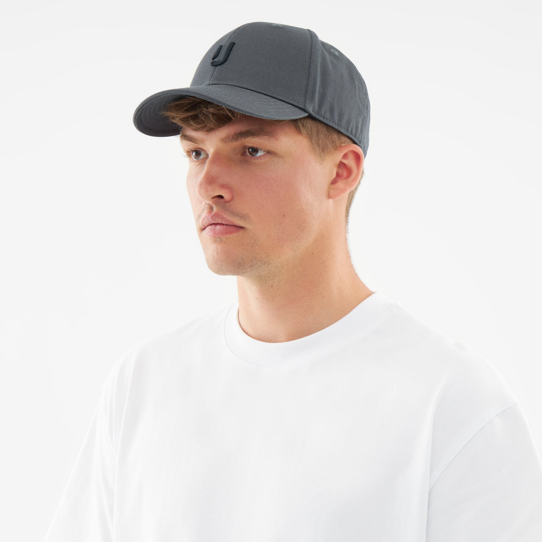 Mann trägt anthrazitgraue Snapback-Cap 'Jason' mit gebogenem Schirm und weißes T-Shirt