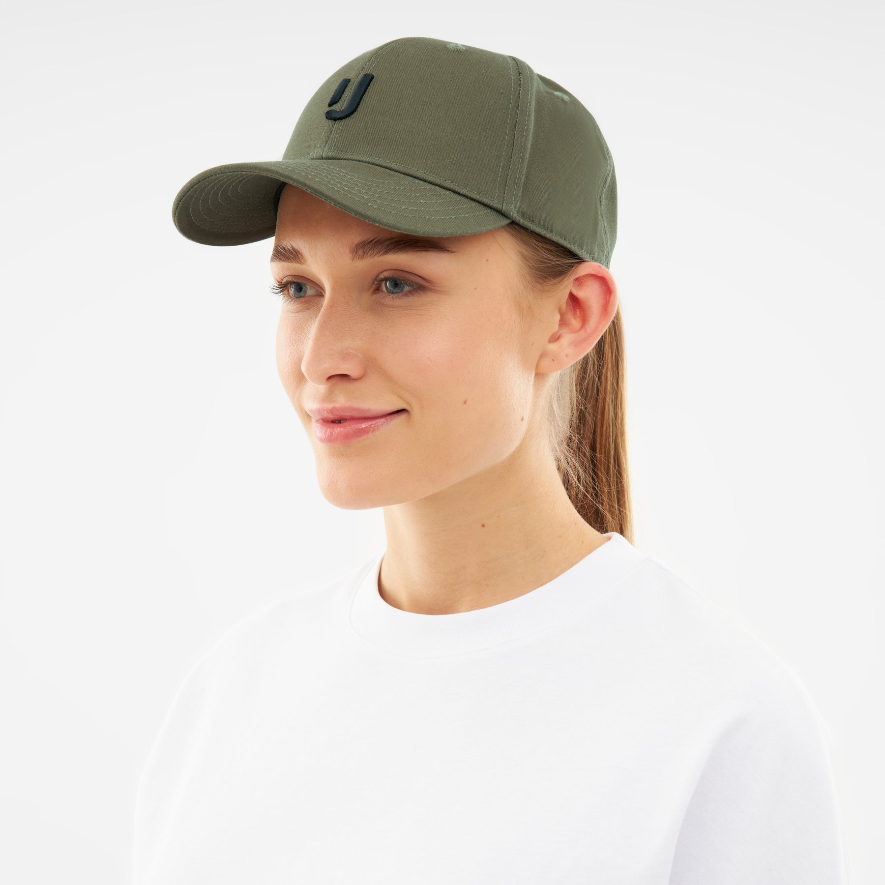 Frau trägt olivgrüne Snapback-Cap 'Jason' mit nahtlosem Visier und schwarzem 'J'-Logo
