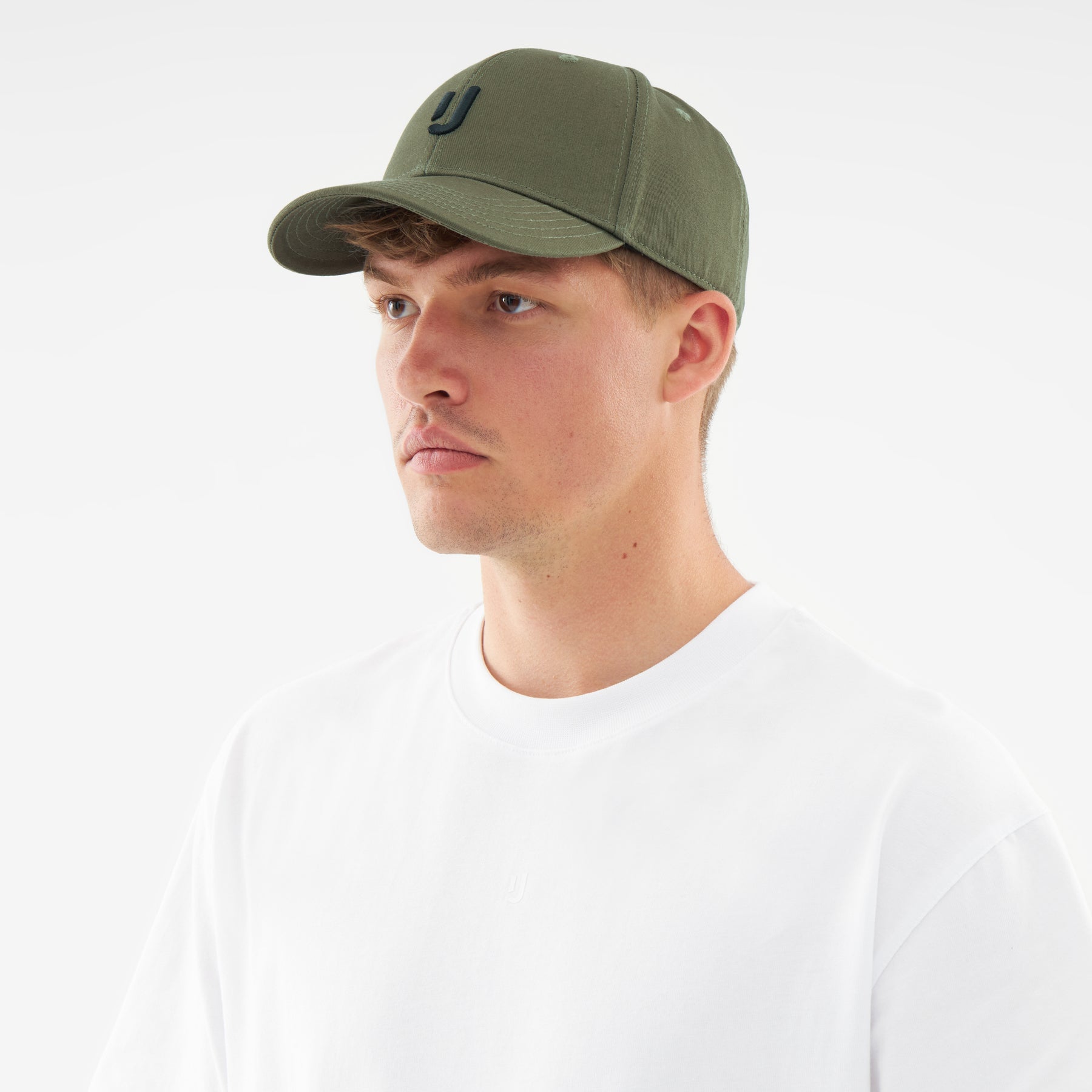 Mann trägt olivgrüne Snapback-Cap 'Jason' mit schwarzem Logo und weißem T-Shirt