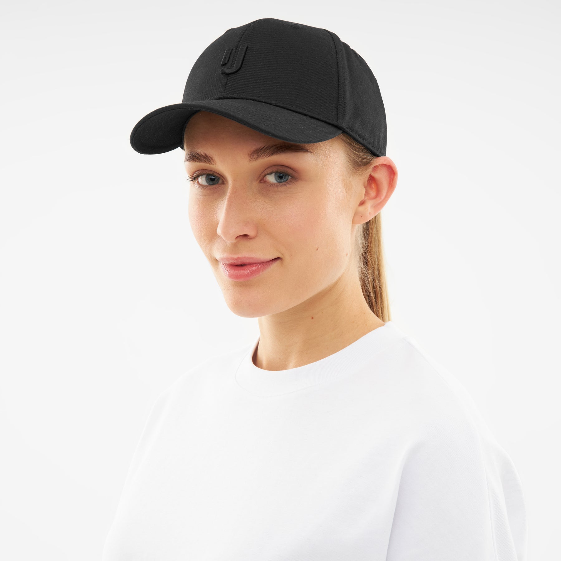 Frau trägt schwarzen Snapback Cap 'Jason' mit dezentem 'J'-Logo, weiße Shirt