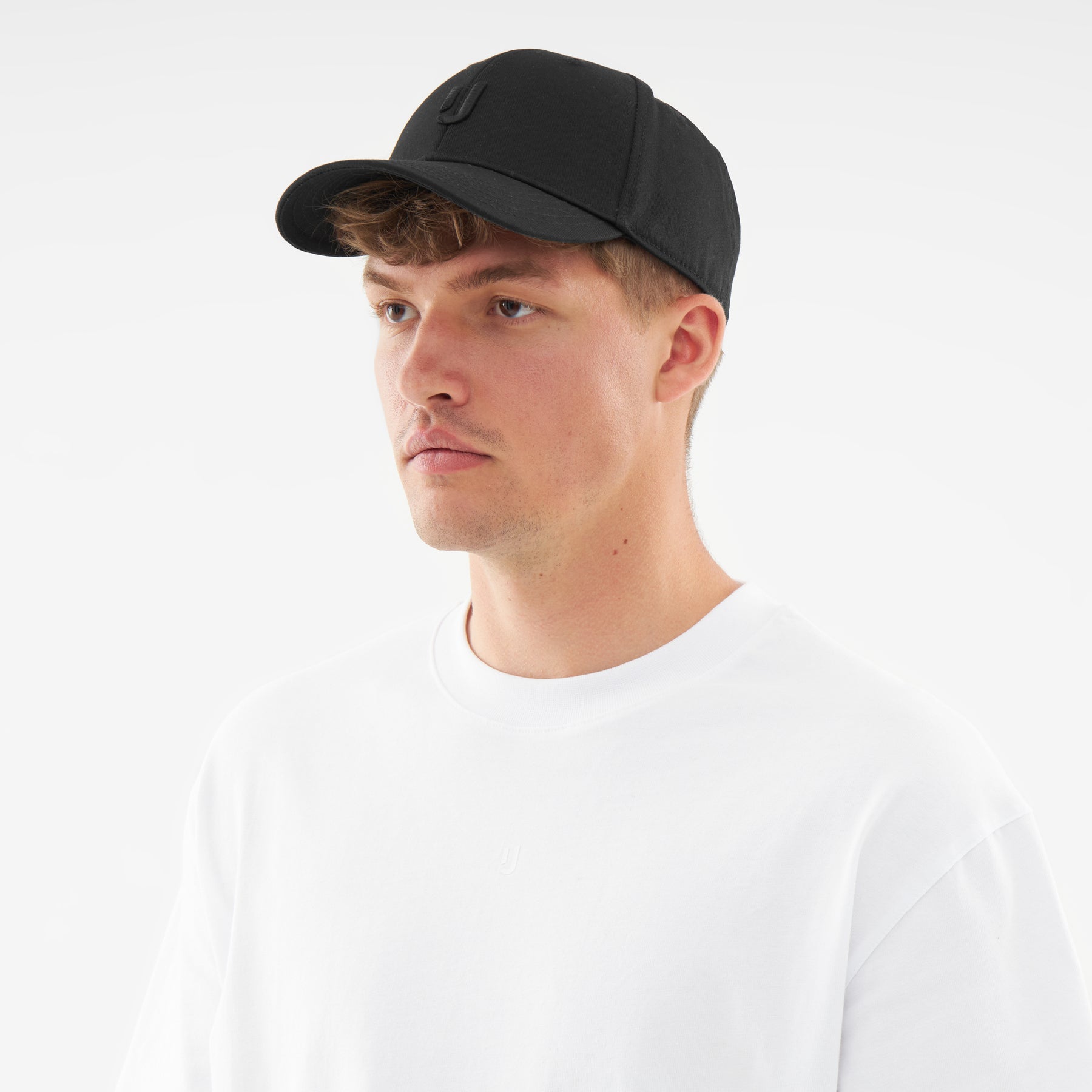 Mann mit schwarzer Johnny Urban Snapback Cap 'Jason' und weißem T-Shirt