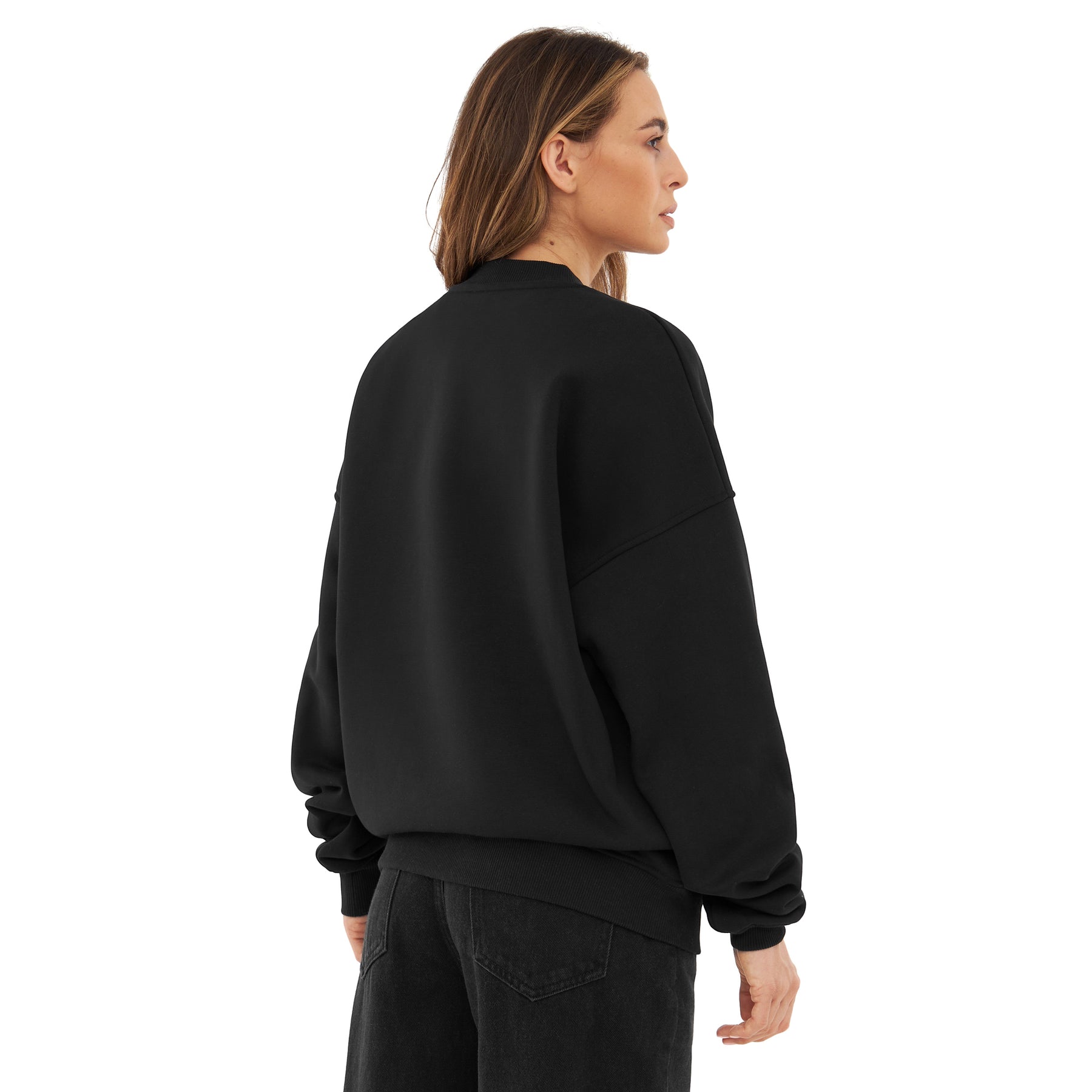 Dame von hinten mit oversized schwarzem Crewneck 'Carter' und schwarzen Jeans