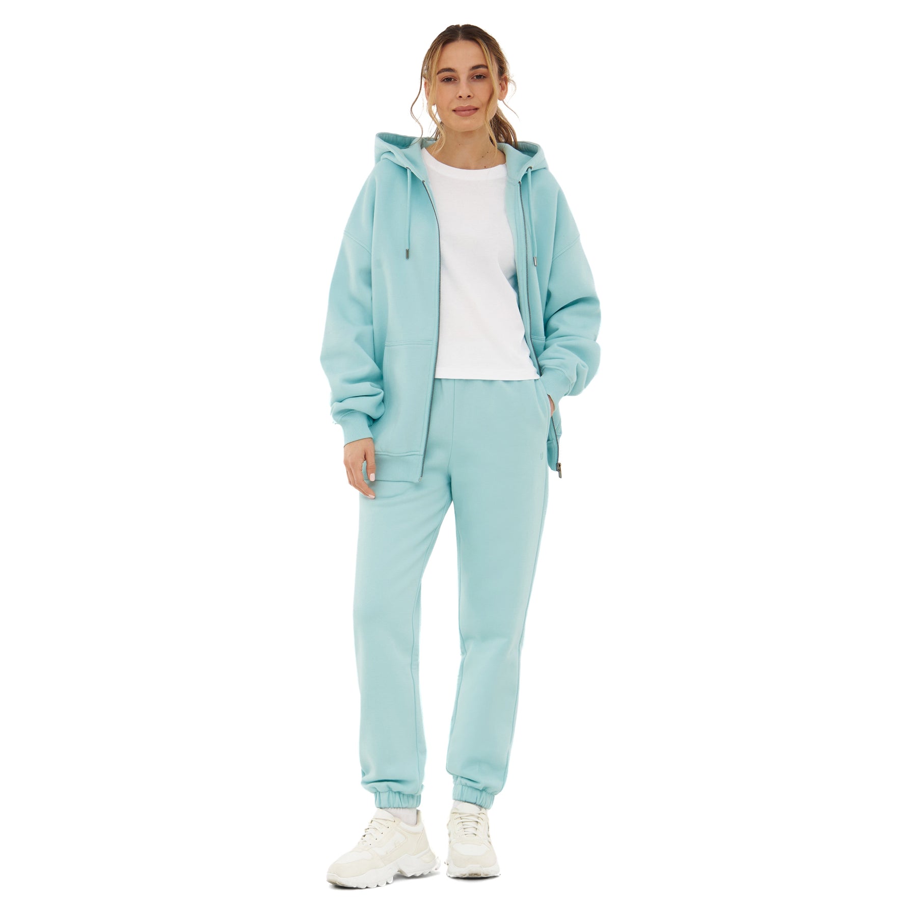 Frau trägt Jogginghose 'Owen' in Ice-Blau mit passendem Kapuzenpullover und weißem T-Shirt
