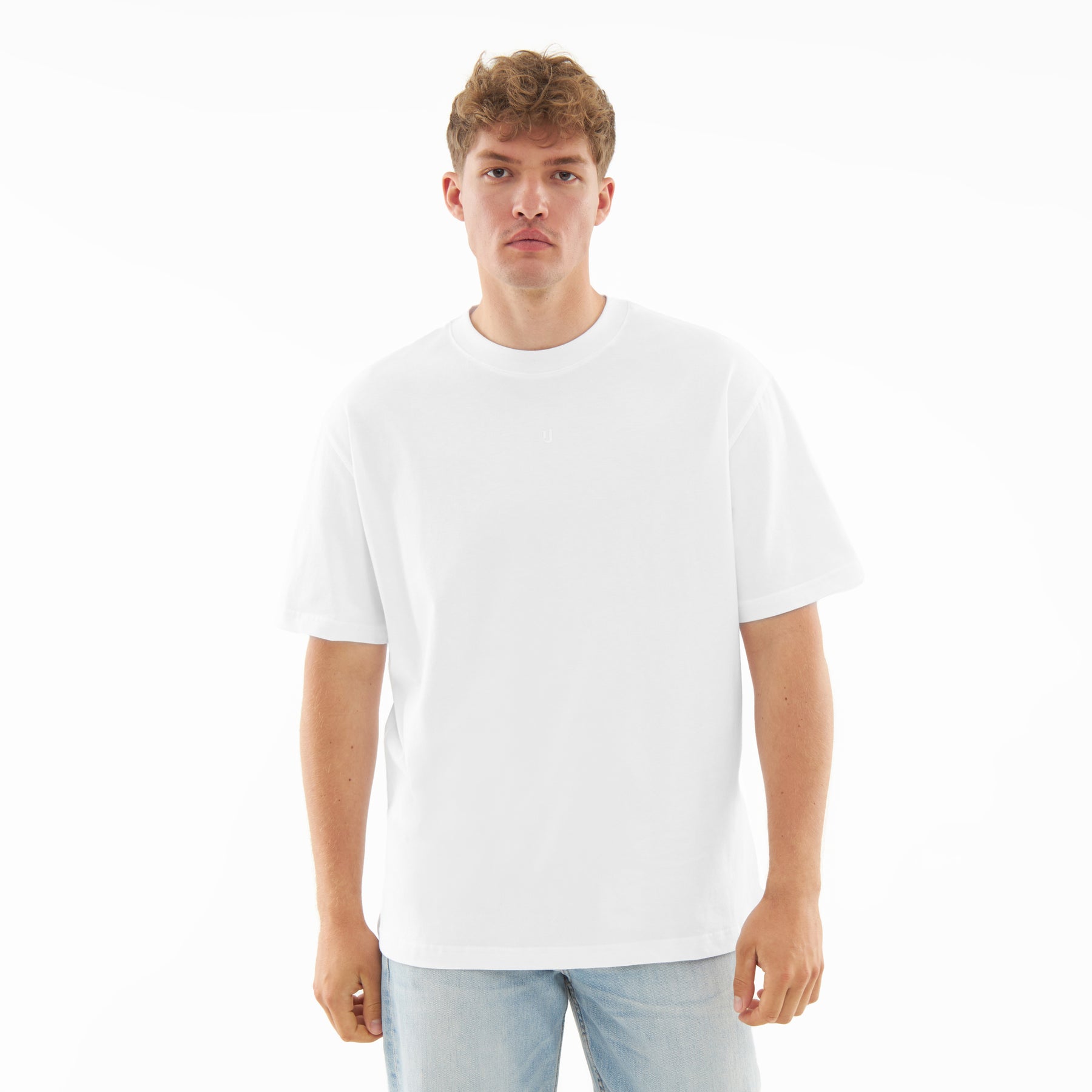 Mann mit neutralem Gesichtsausdruck trägt weißes T-Shirt "Sammy Butterfly" und helle Jeans