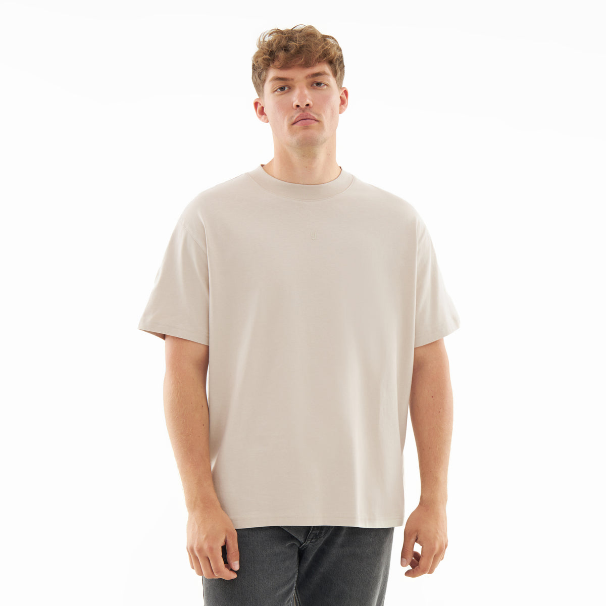 Mann trägt beige oversized T-Shirt 'Sammy Butterfly' und dunkle Jeans