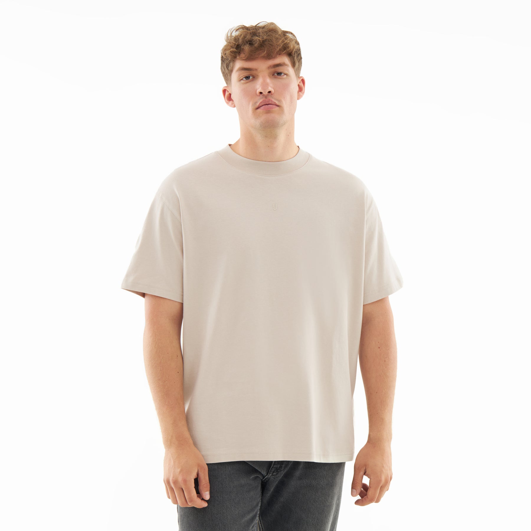 Mann trägt beige oversized T-Shirt 'Sammy Butterfly' und dunkle Jeans
