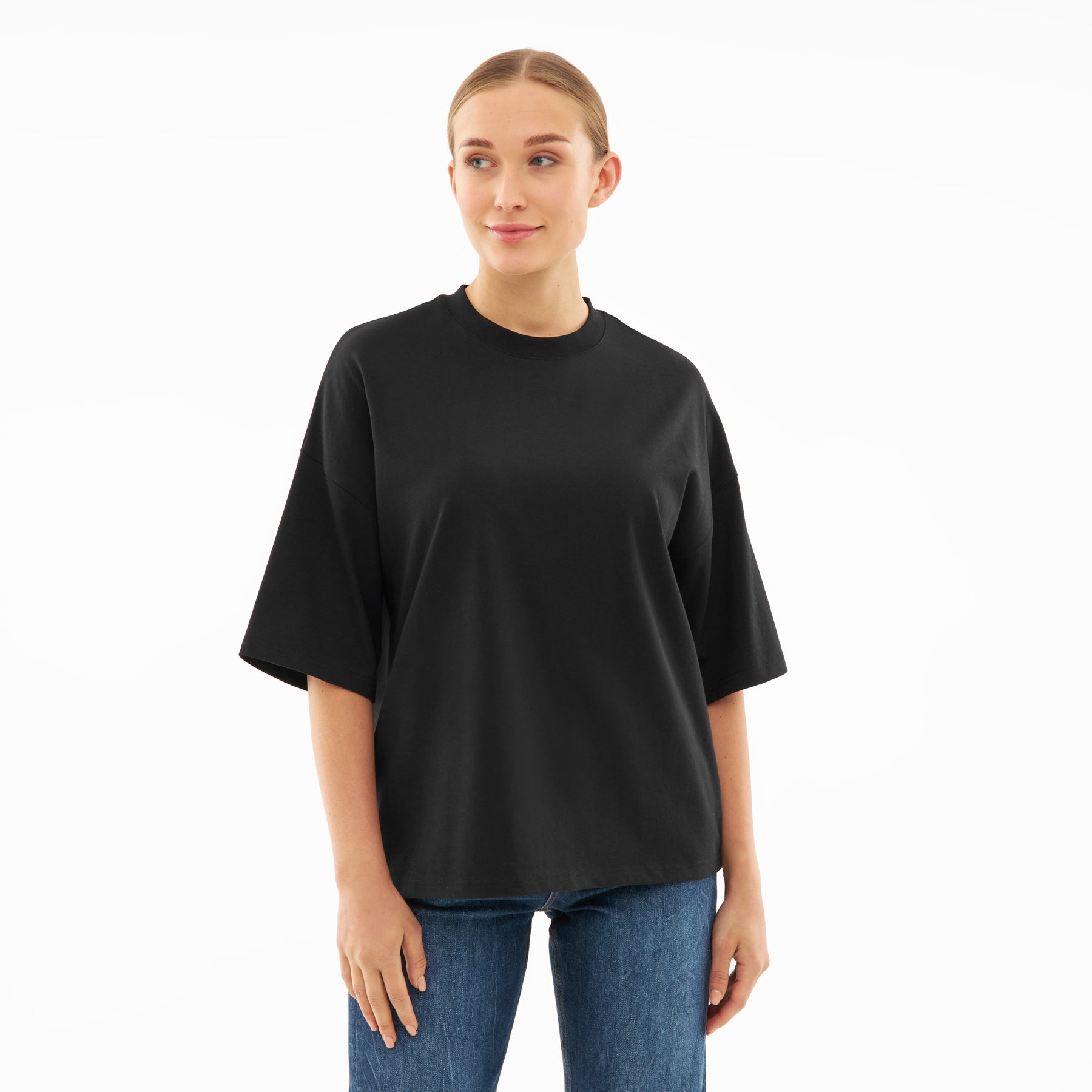 Frau trägt schwarzes Oversize-T-Shirt 'Vic' mit kurzen Ärmeln und blauer Jeans