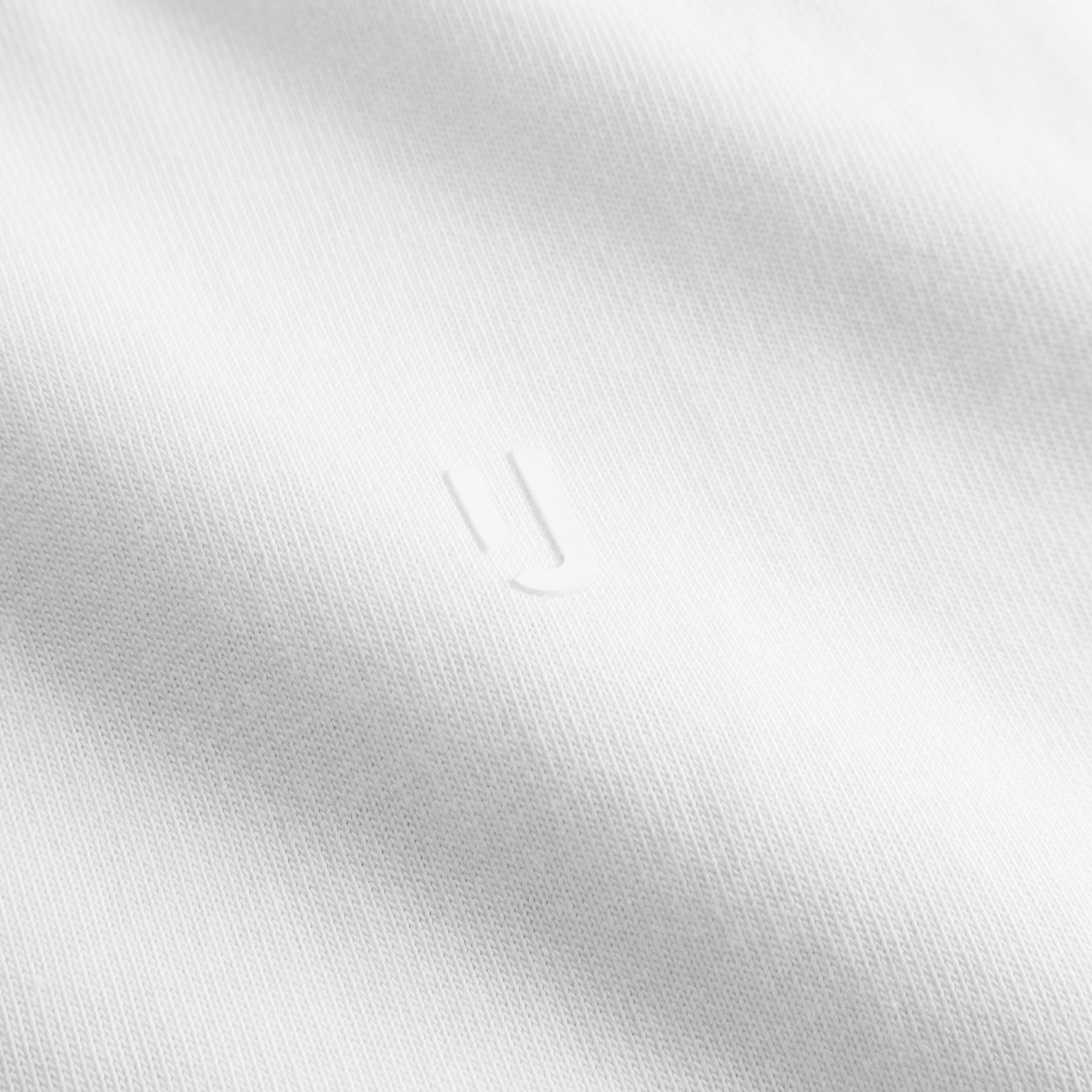 Nahaufnahme des weißen Stoffs des T-Shirts 'Sammy Chrome Butterfly' mit geprägtem Johnny Urban Logo