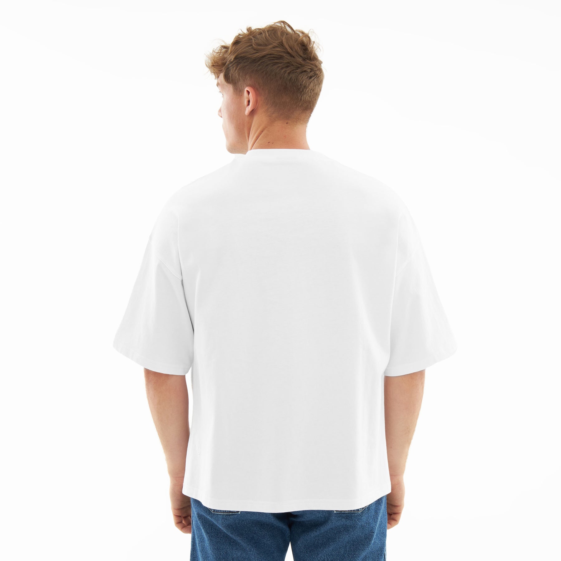 Mann trägt weißes, locker geschnittenes T-Shirt 'Vic' von hinten, kombiniert mit blauer Jeans