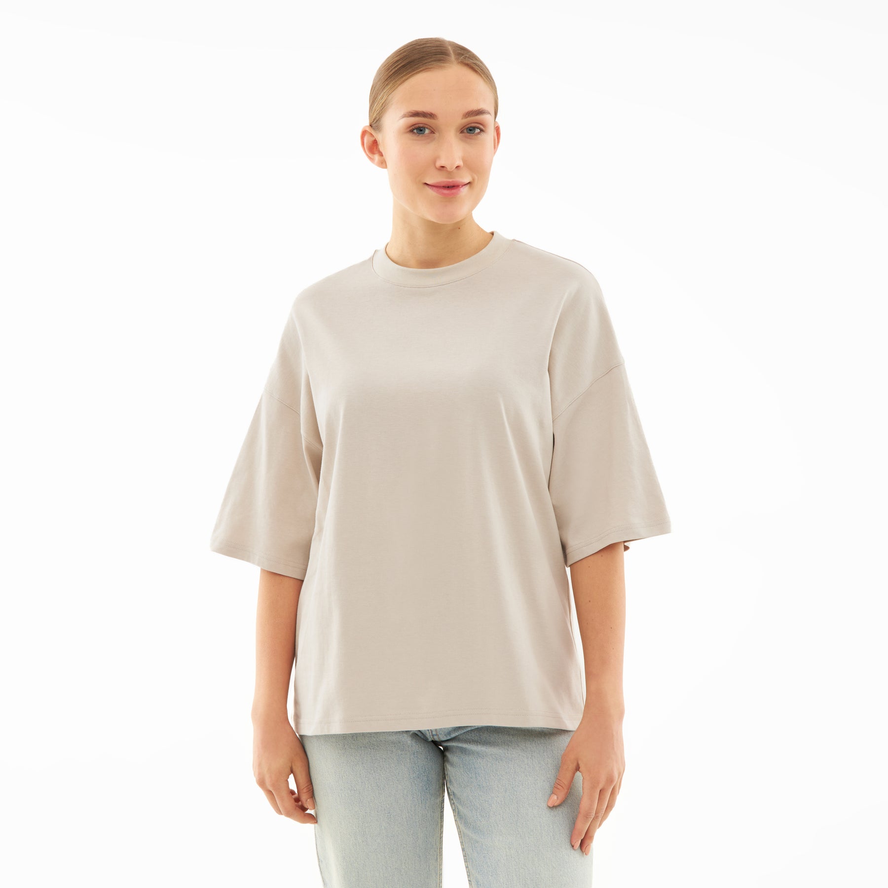 Beige T-Shirt 'Vic' mit kurzem, weitem Schnitt, getragen von Frau mit zusammengebundenen Haaren
