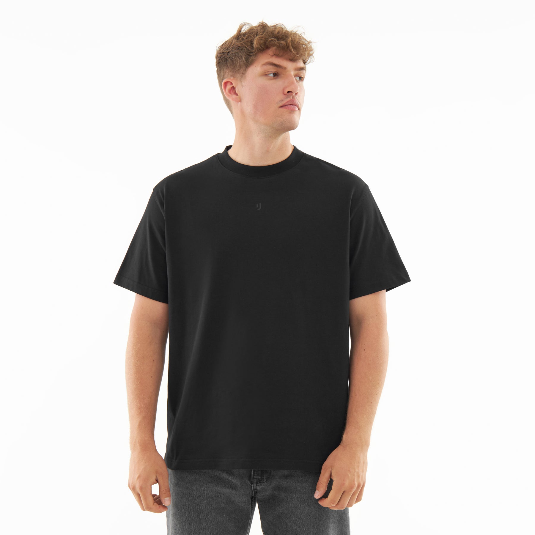 Mann trägt schwarzes Oversize-T-Shirt 'Sammy Butterfly' mit kleinem Logo vorn