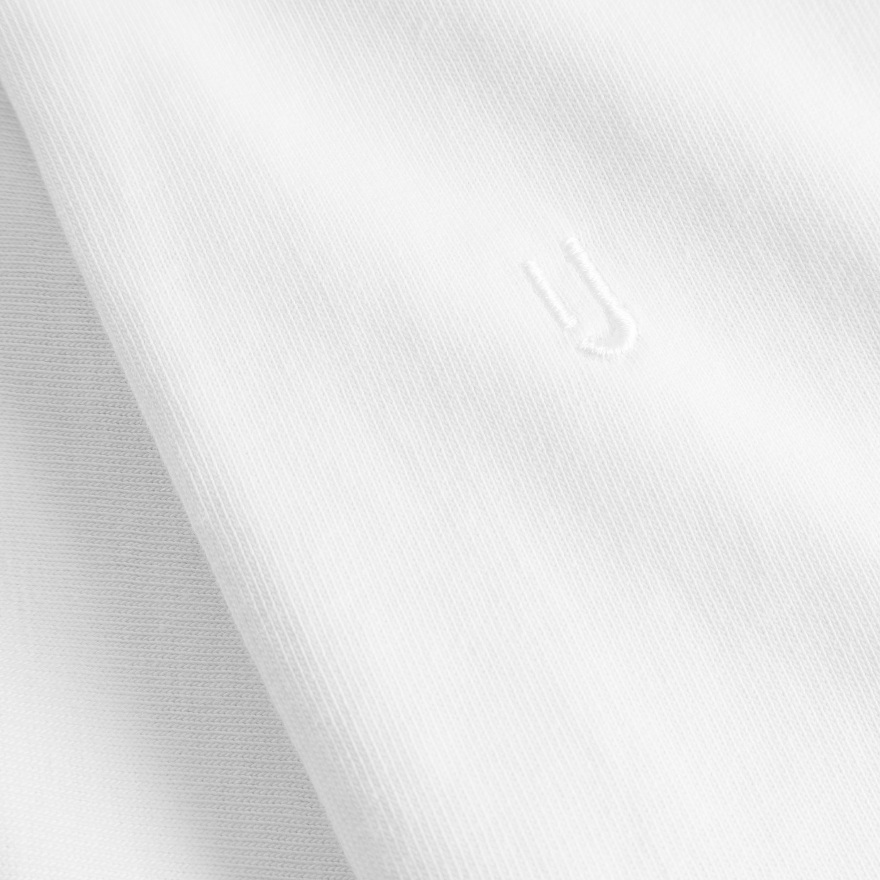 Weiße Textilstruktur mit dezentem, weiß gesticktem Johnny Urban Logo